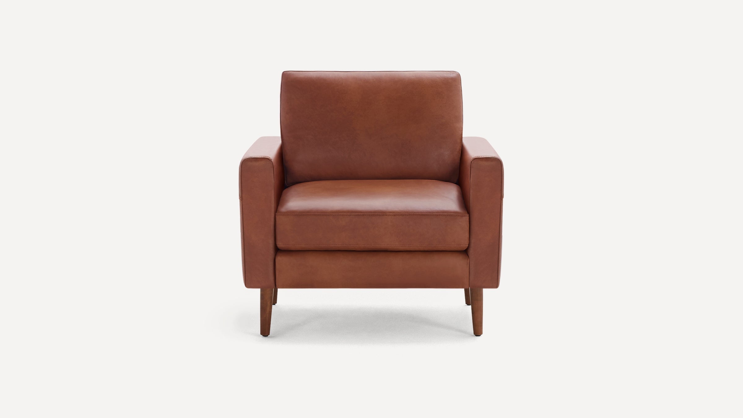 Front view of a modern, brown leather armchair with straight arms and wooden legs on a white background.
