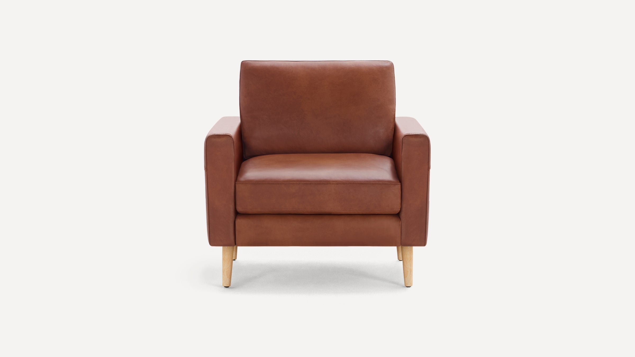 Brown leather armchair with wooden legs, featuring a cushioned seat and backrest against a plain white background.