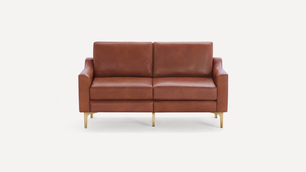 Two-seater brown leather sofa with cushioned back and seat, supported by four slim golden metal legs.