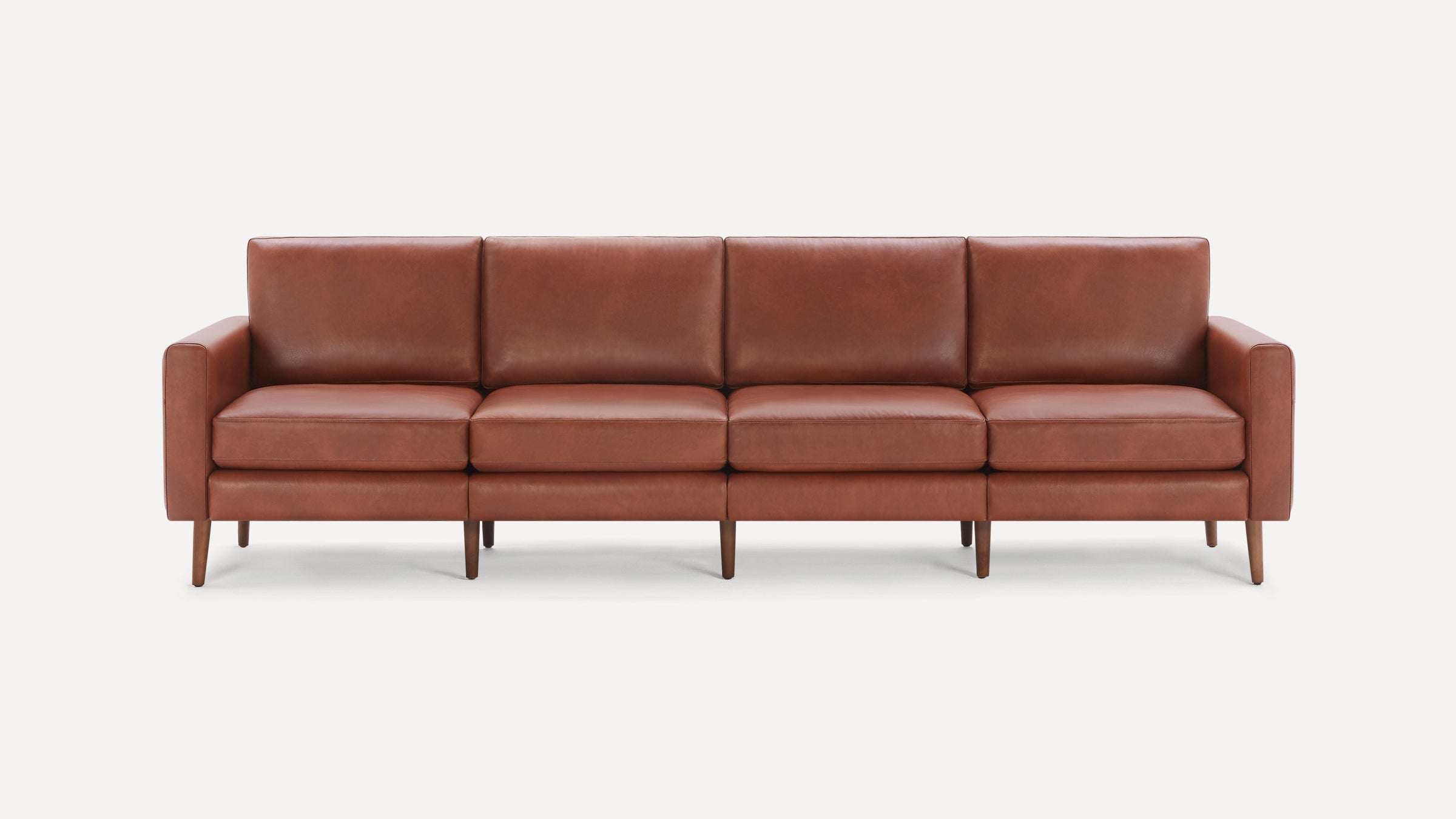 Four-seat modern sofa with smooth brown leather upholstery and wooden legs against a plain white background.