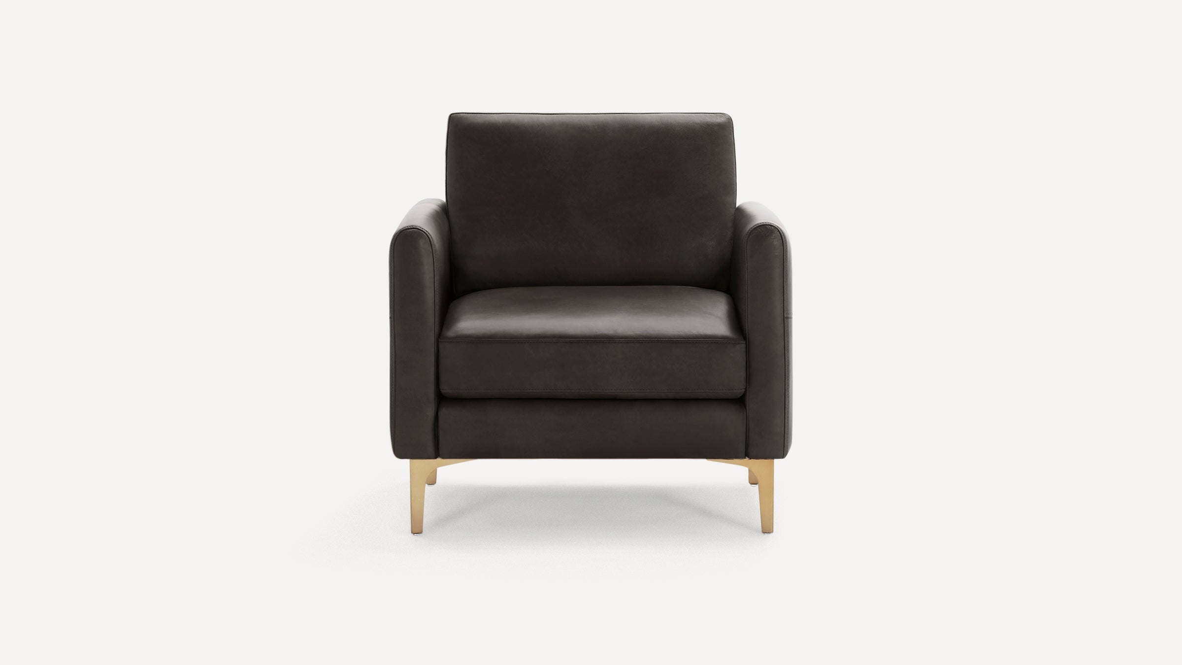 Front view of a modern dark gray leather armchair with slim gold metal legs and square armrests on a white background.