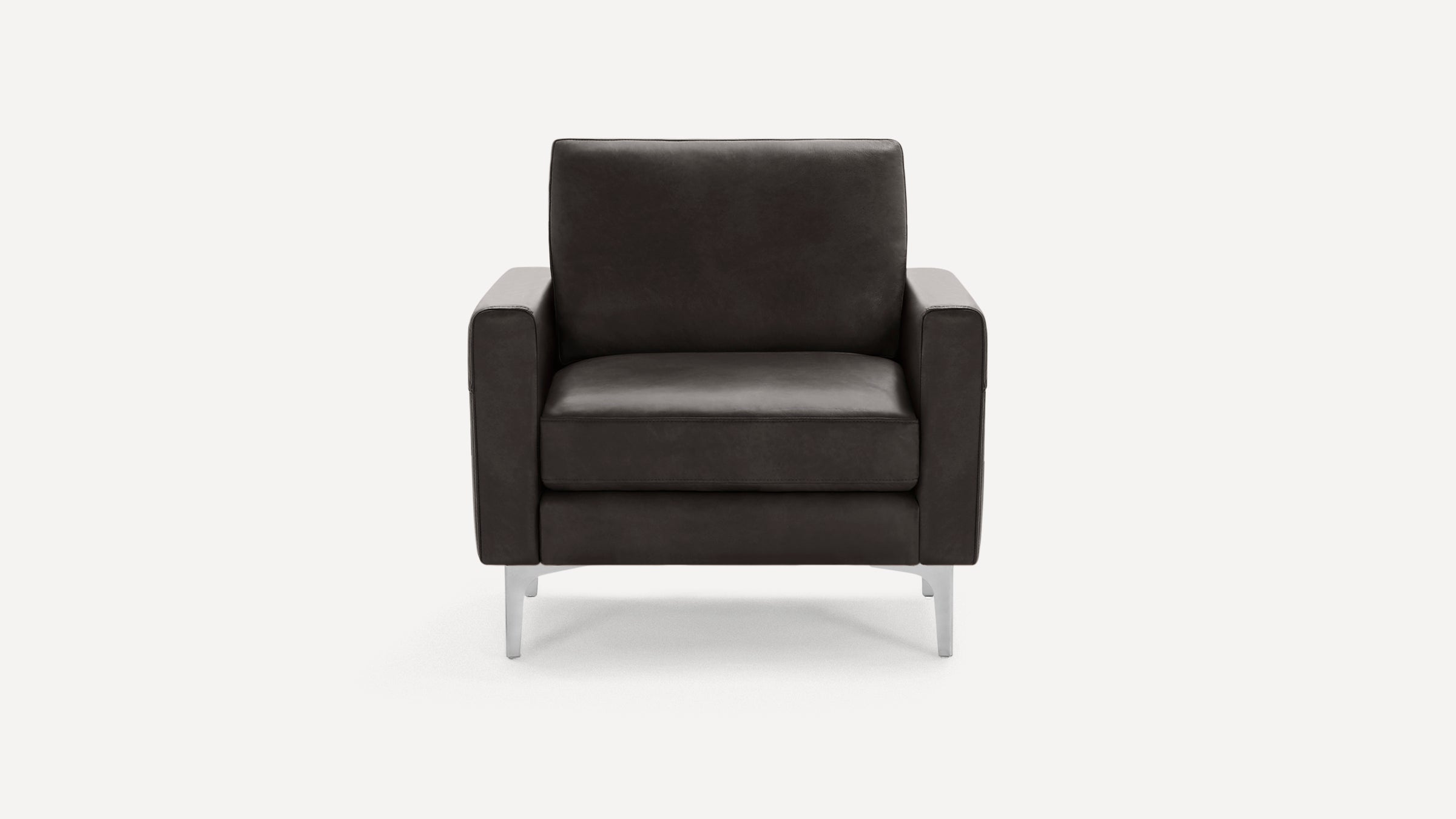 Front view of a modern, dark gray leather armchair with wide armrests and silver metal legs, against a plain background.