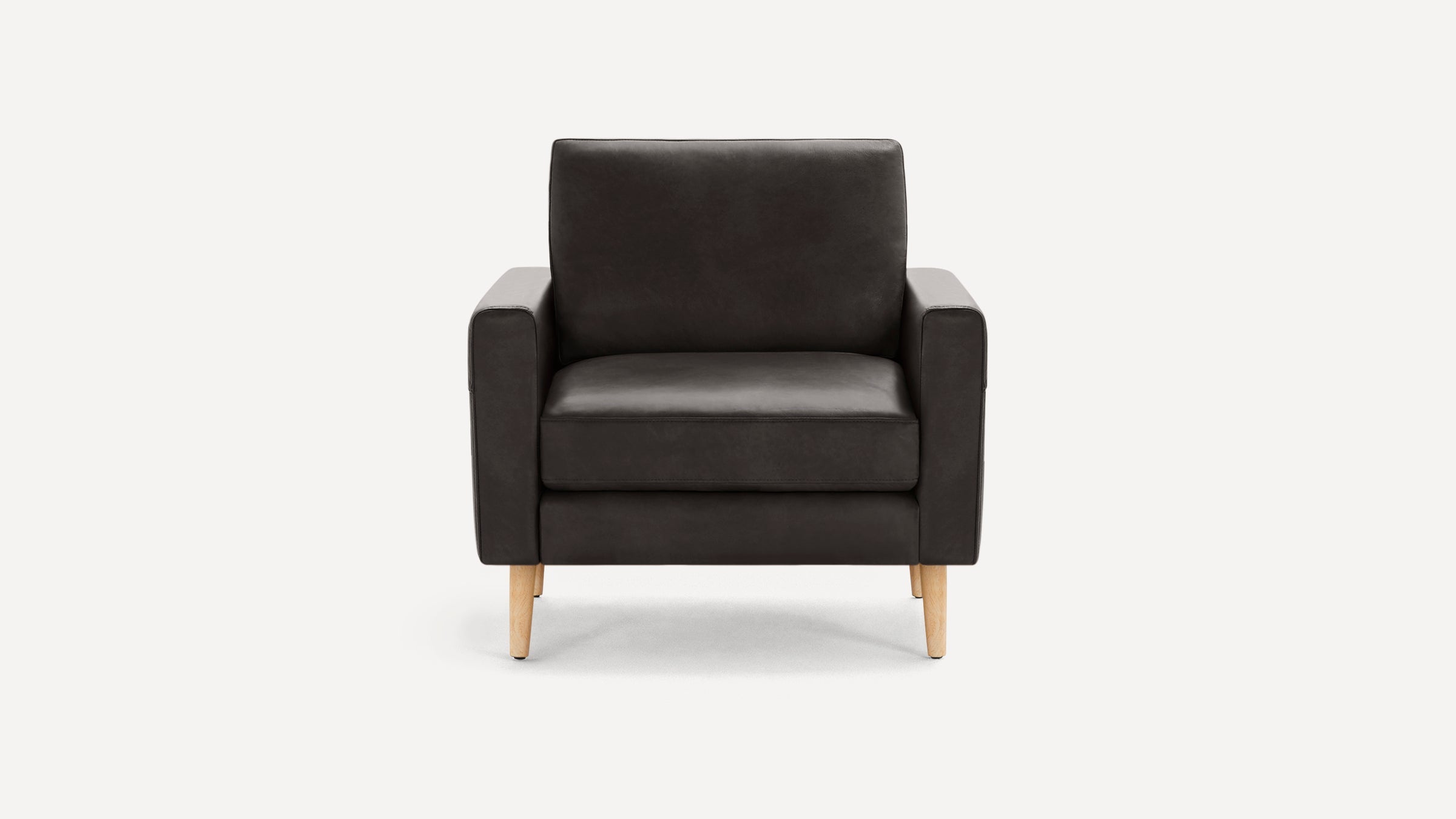 Dark gray modern armchair with boxy design, thick cushions, and light wooden legs against a white background.