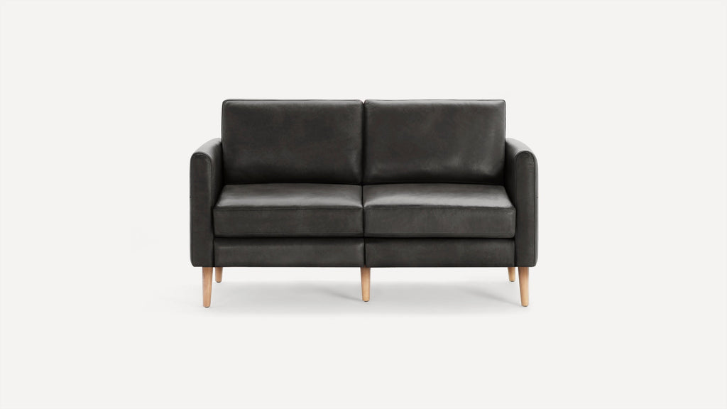 Modern dark gray leather two-seater sofa with straight arms and light wooden tapered legs, set against a plain white background.