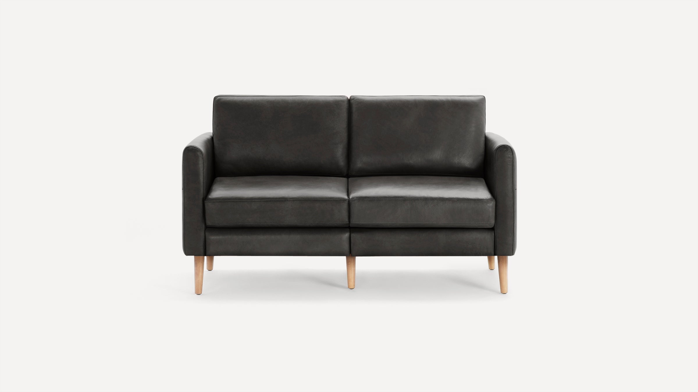 Modern dark gray leather two-seater sofa with straight arms and light wooden tapered legs, set against a plain white background.