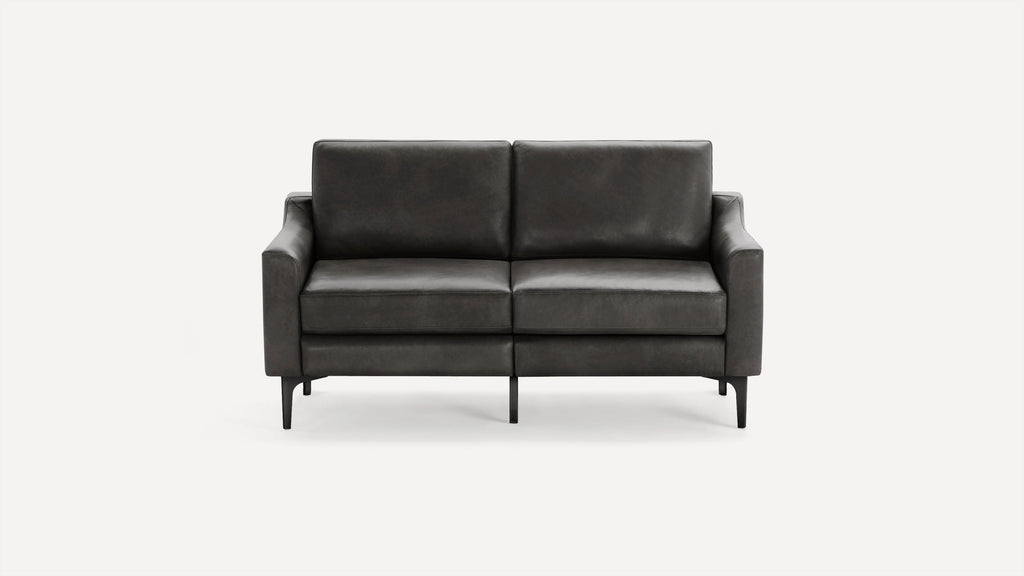 Modern dark gray leather loveseat with squared armrests and thin black metal legs on white background.