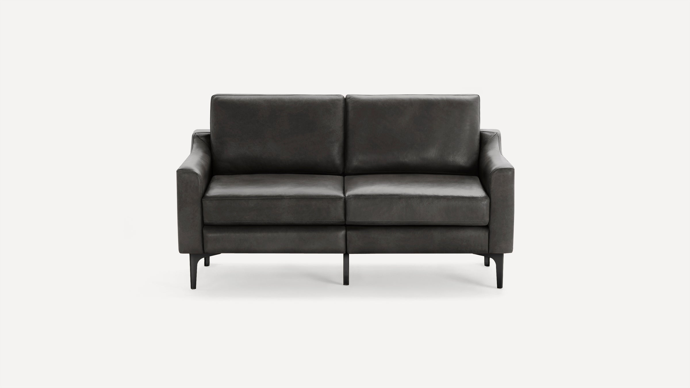 Modern dark gray leather loveseat with squared armrests and thin black metal legs on white background.