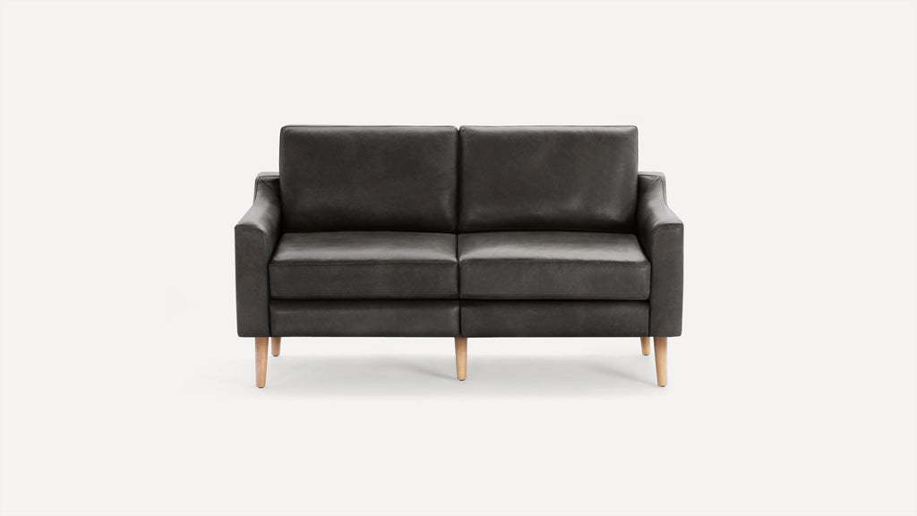 Modern black leather two-seater sofa with clean lines, square arms, and natural wooden tapered legs on white background.