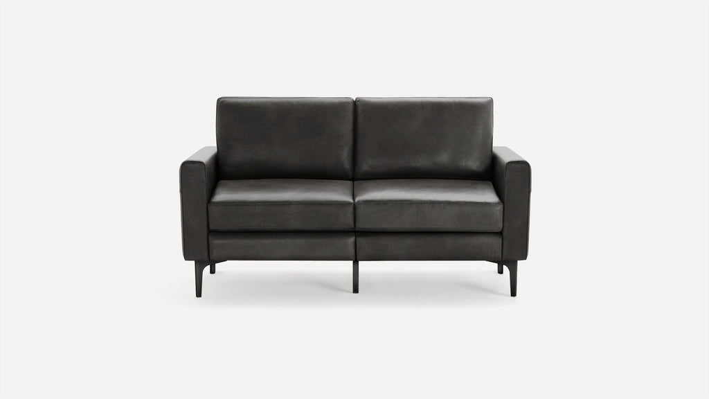 Modern dark gray leather loveseat with straight armrests and slim black legs on a white background.