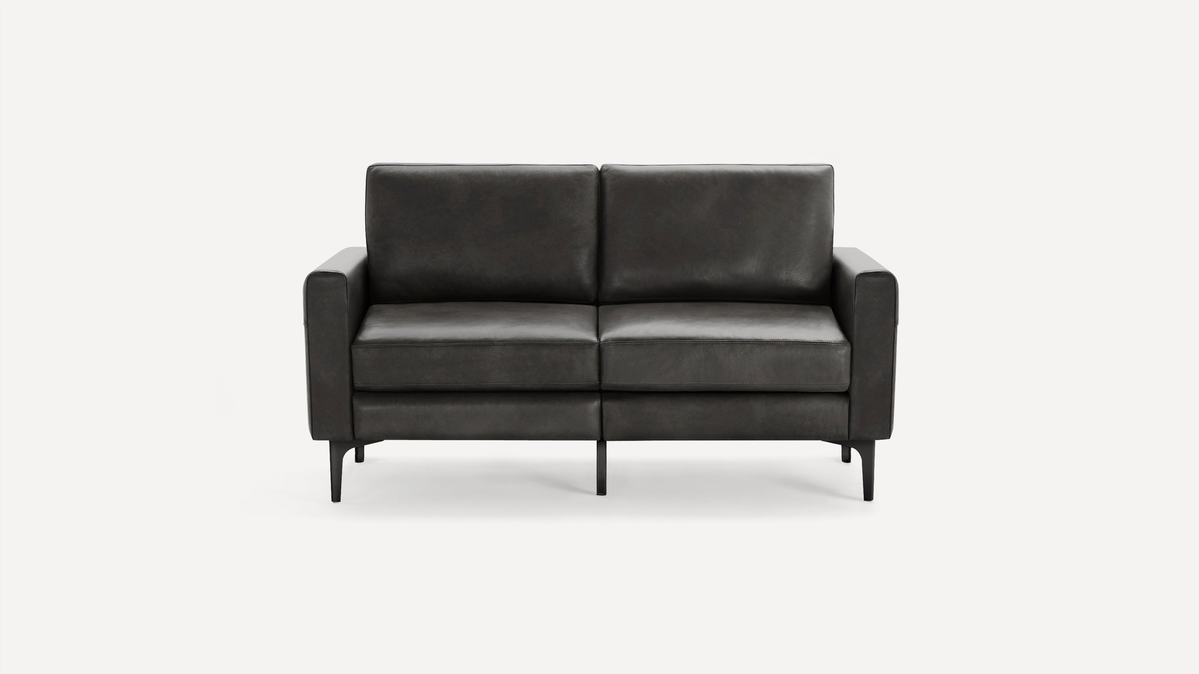 Modern dark gray leather loveseat with straight armrests and slim black legs on a white background.