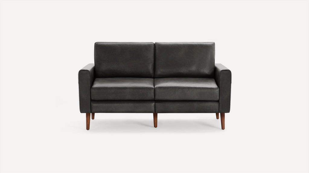 Two-seater black leather sofa with clean lines and wooden legs on a white background.