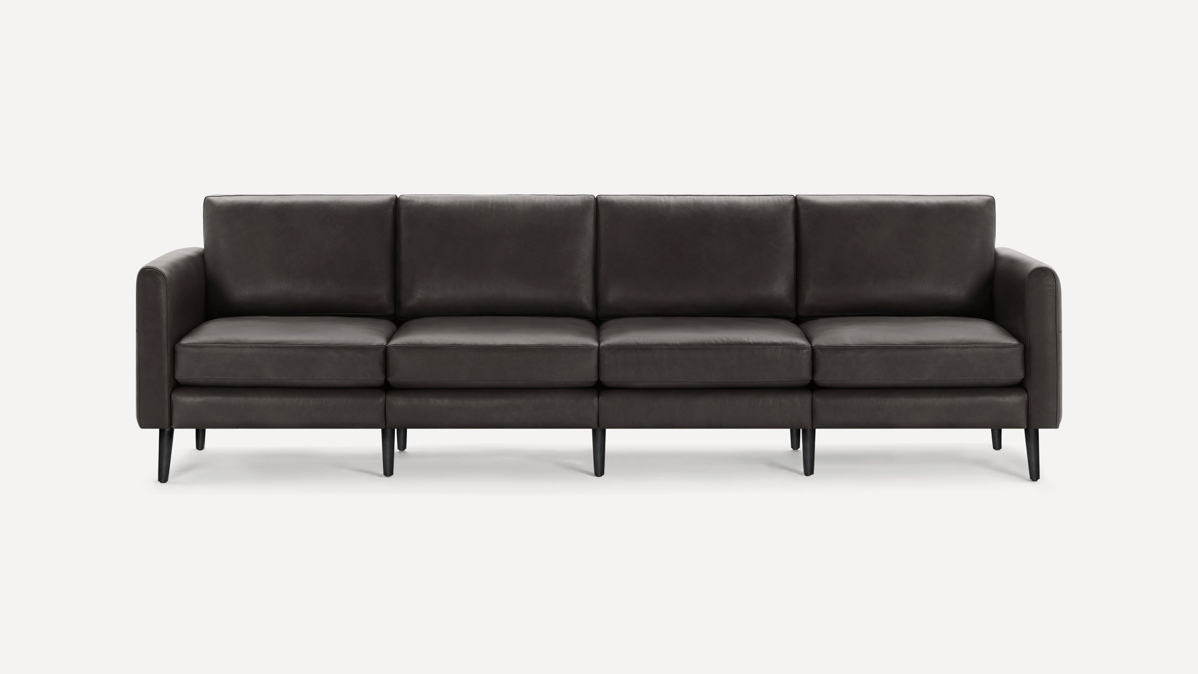 Four-seat modern dark gray leather sofa with straight armrests and black tapered legs on white background.