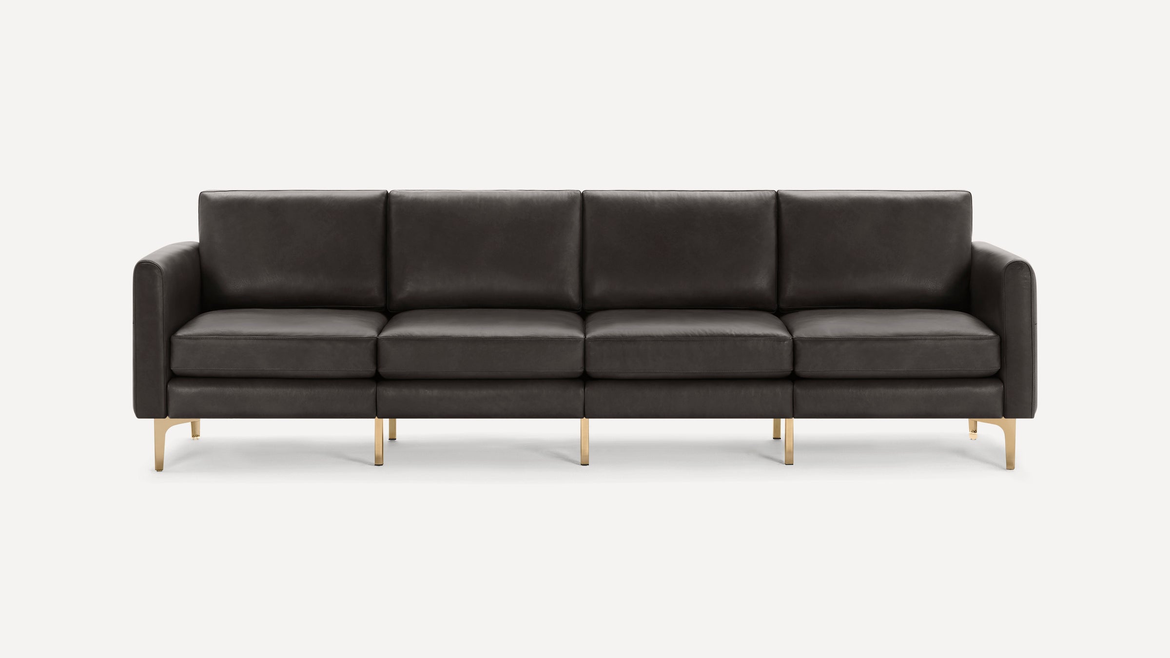 Modern four-seater sofa in dark gray leather with slim gold metal legs and straight armrests on a white background.