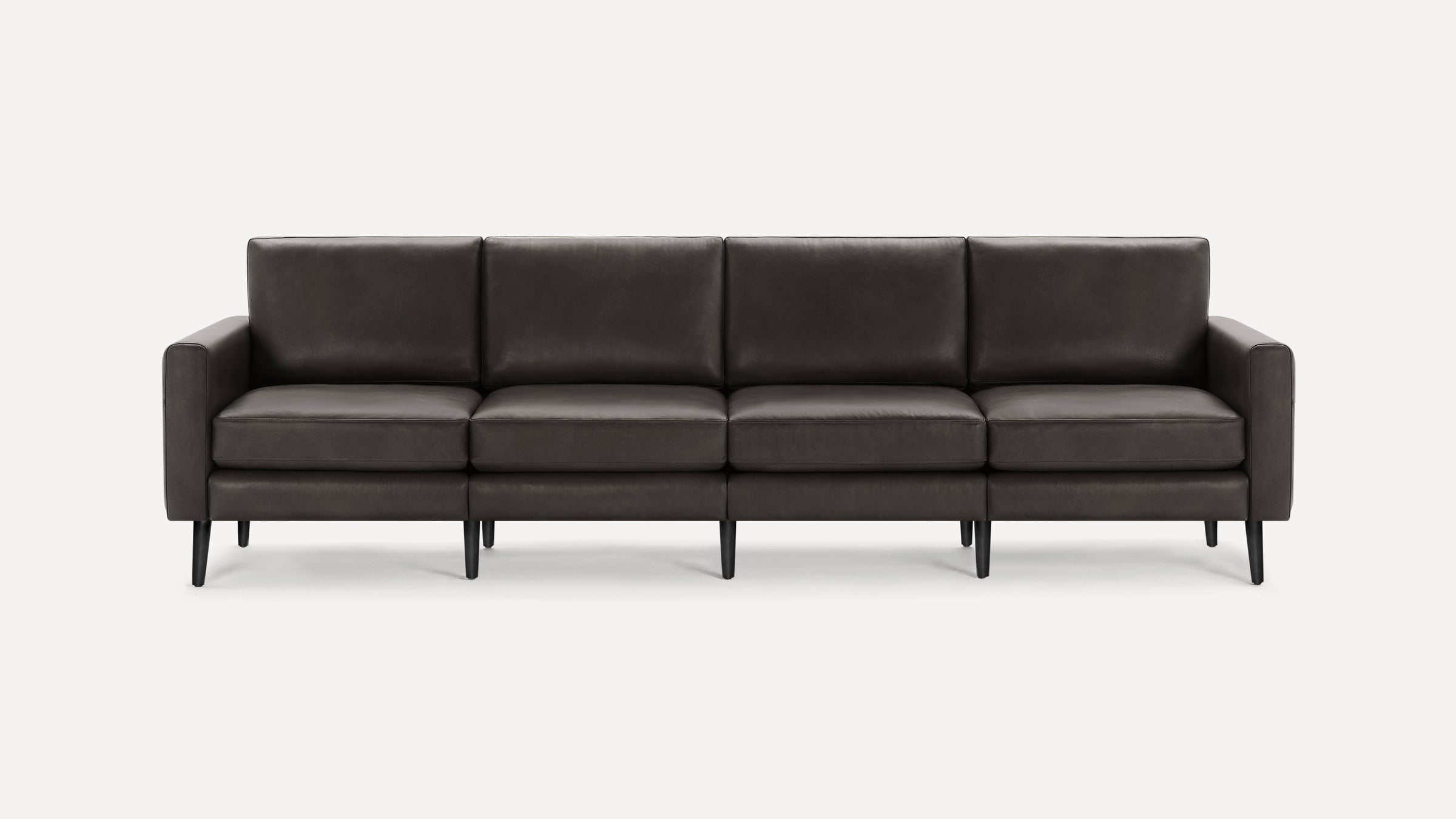 Modern four-seater sofa with dark gray leather upholstery, straight armrests, and slender black legs on a white background.