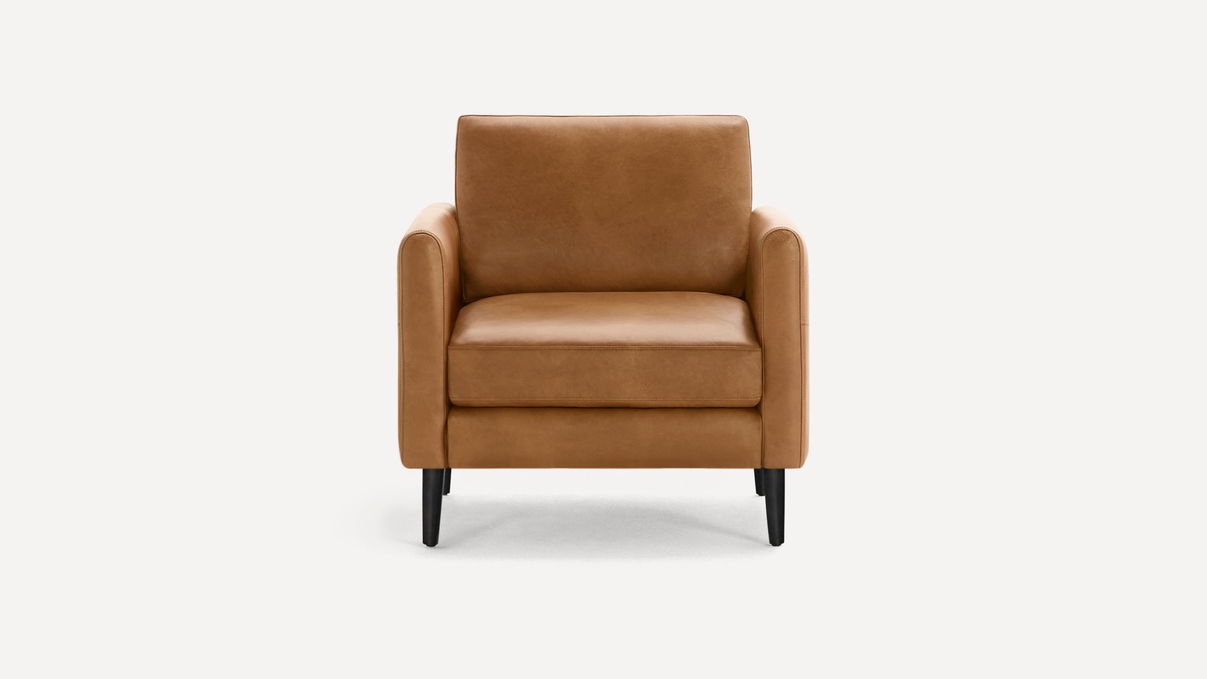 Front view of a modern brown leather armchair with smooth cushioning and black tapered wooden legs on a white background.