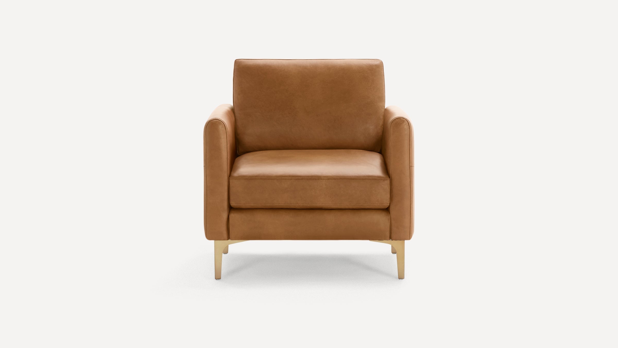 Front view of a modern, tan leather armchair with clean lines and slim gold metal legs on a white background.