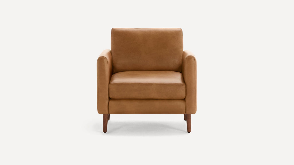 Front view of a mid-century modern caramel brown leather armchair with wooden legs on a white background.