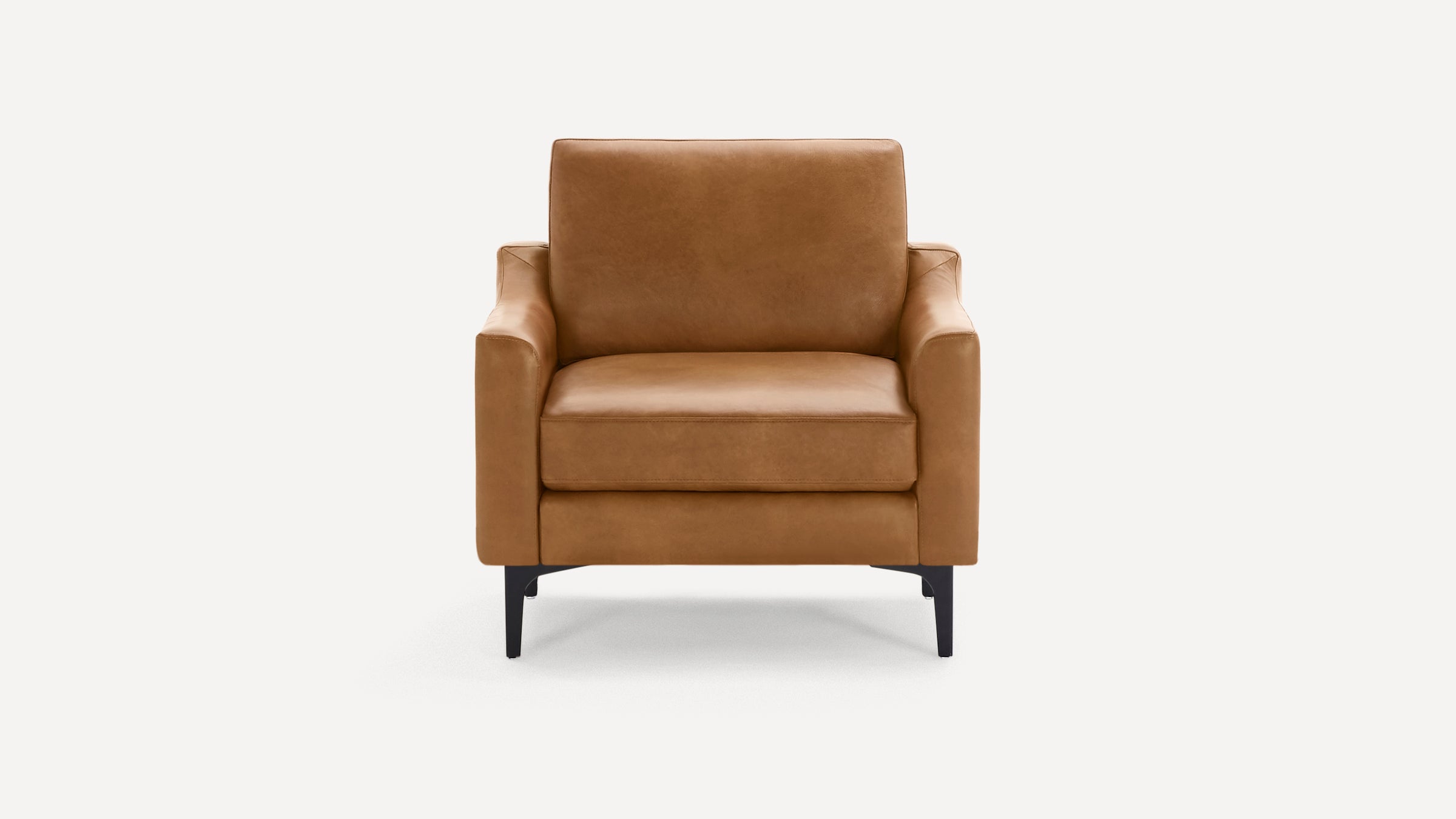 Front view of a modern tan leather armchair with black legs against a plain white background.