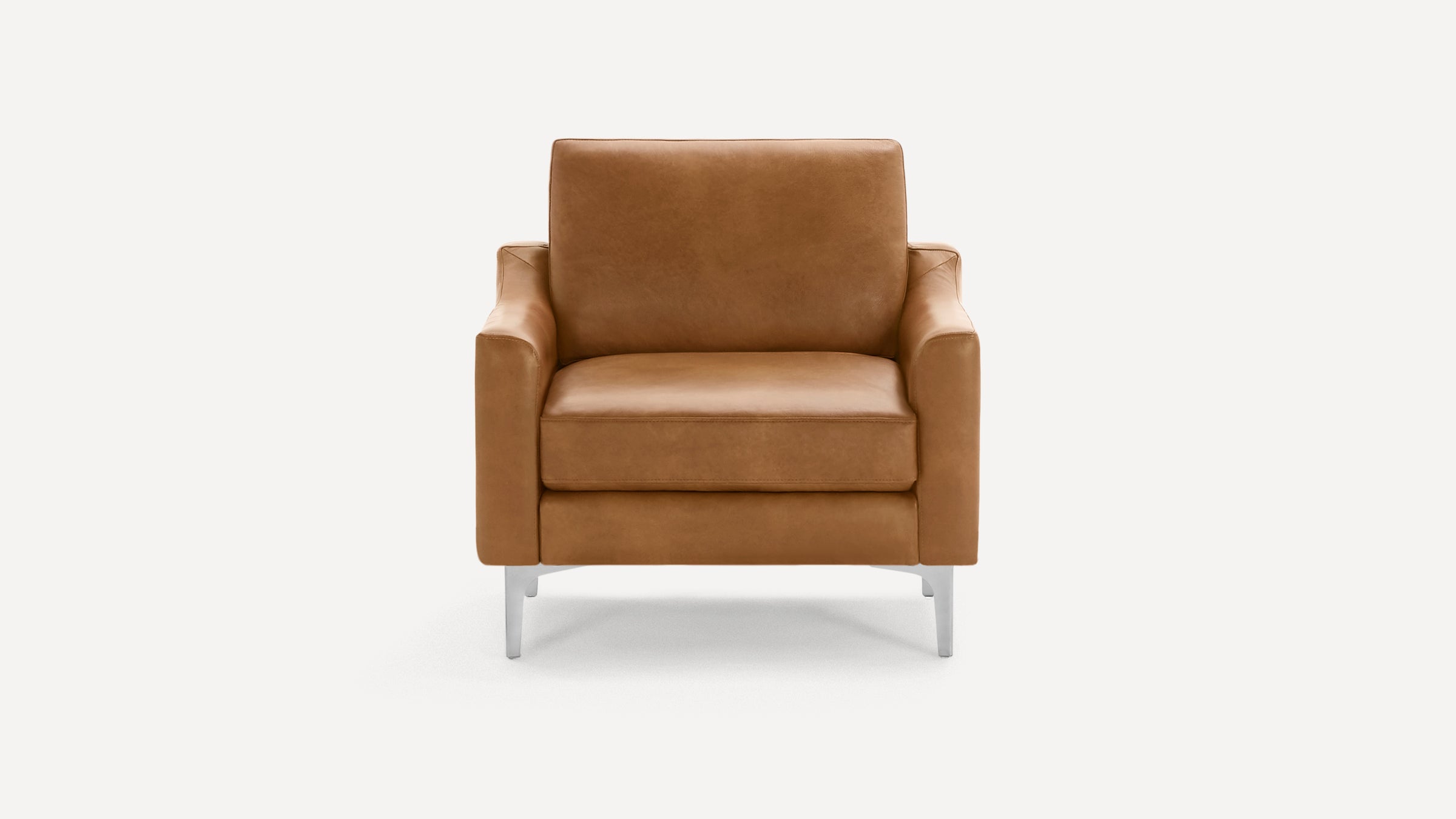 Modern tan leather armchair with clean lines, cushioned seat and back, and sleek silver metal legs on white background.