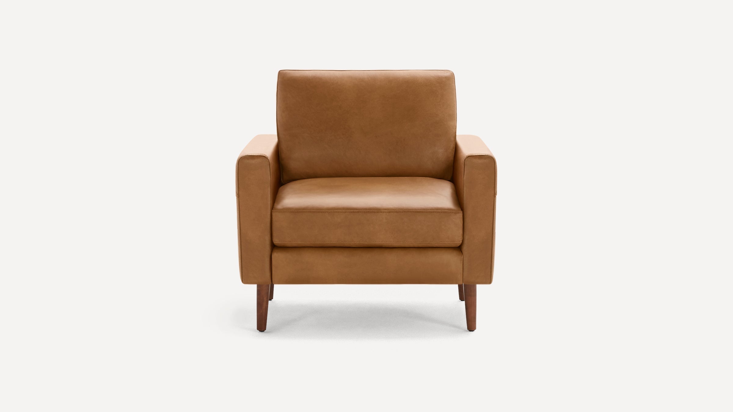 Front view of a mid-century modern tan leather armchair with wooden legs against a plain white background.