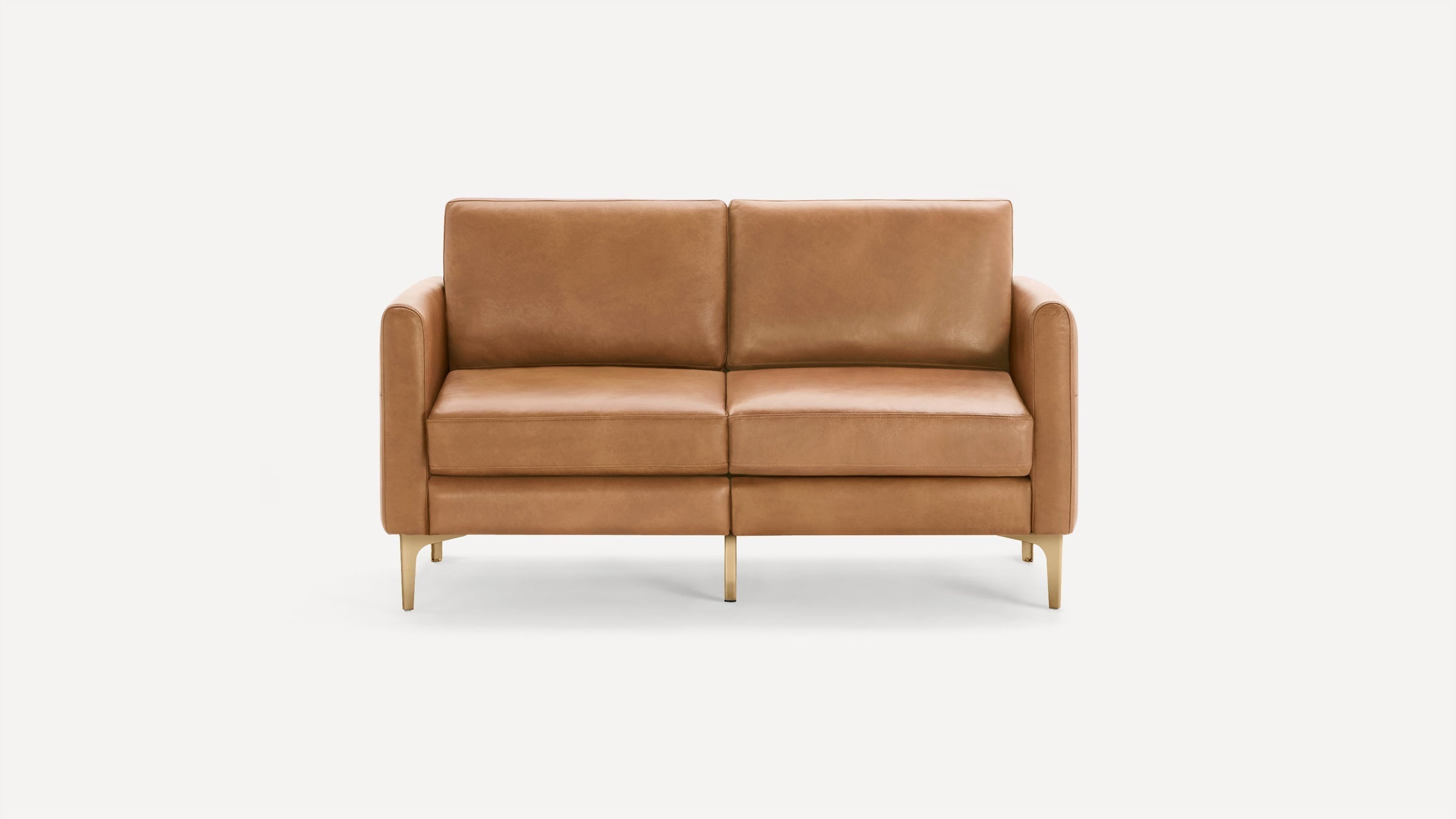 Modern two-seater sofa with light brown leather upholstery and slim gold metal legs, set against a white background.