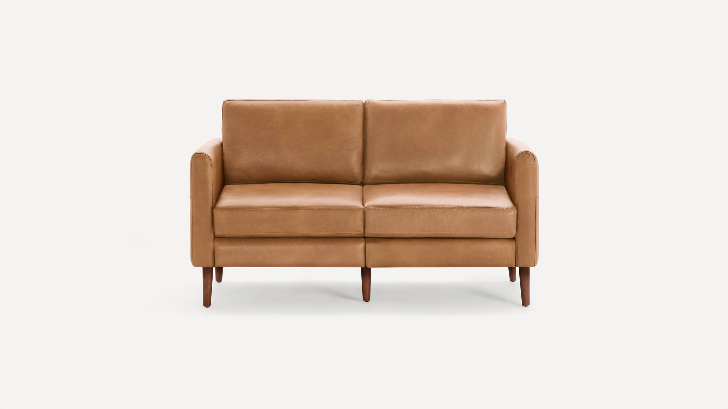 Two-seater sofa with tan leather upholstery and wooden tapered legs, featuring clean, modern lines and plush cushions.