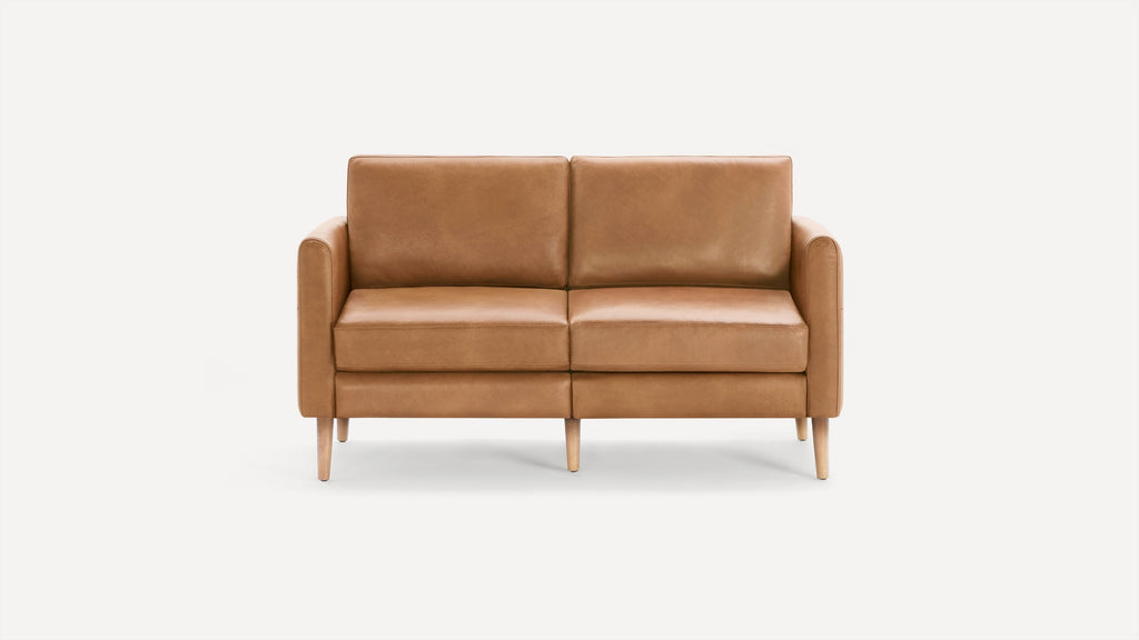 Modern light brown leather loveseat with clean lines, padded cushions, rounded arms, and wooden tapered legs on white background.