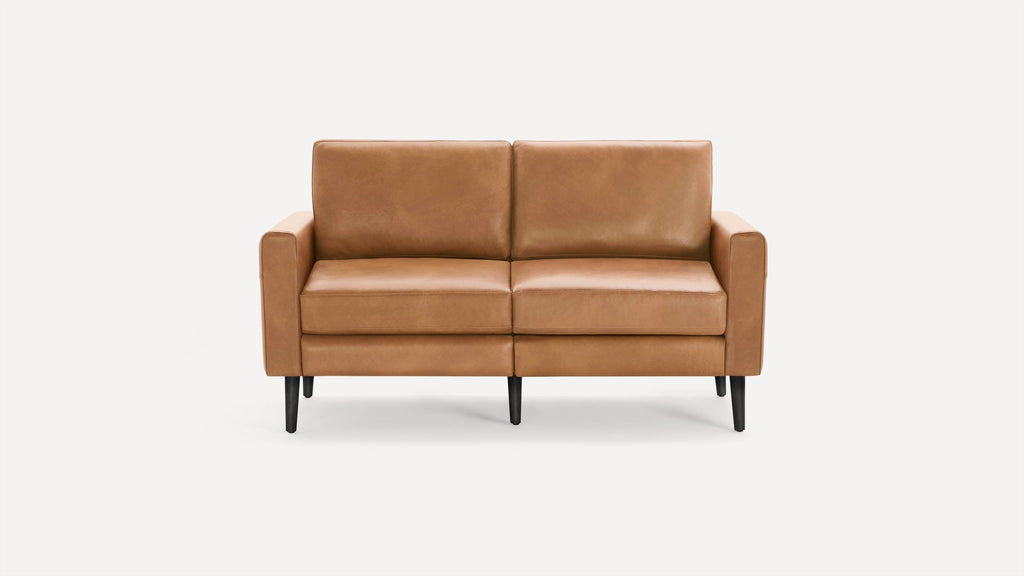 Modern two-seater sofa with light brown leather upholstery and black tapered wooden legs, set against a plain white background.