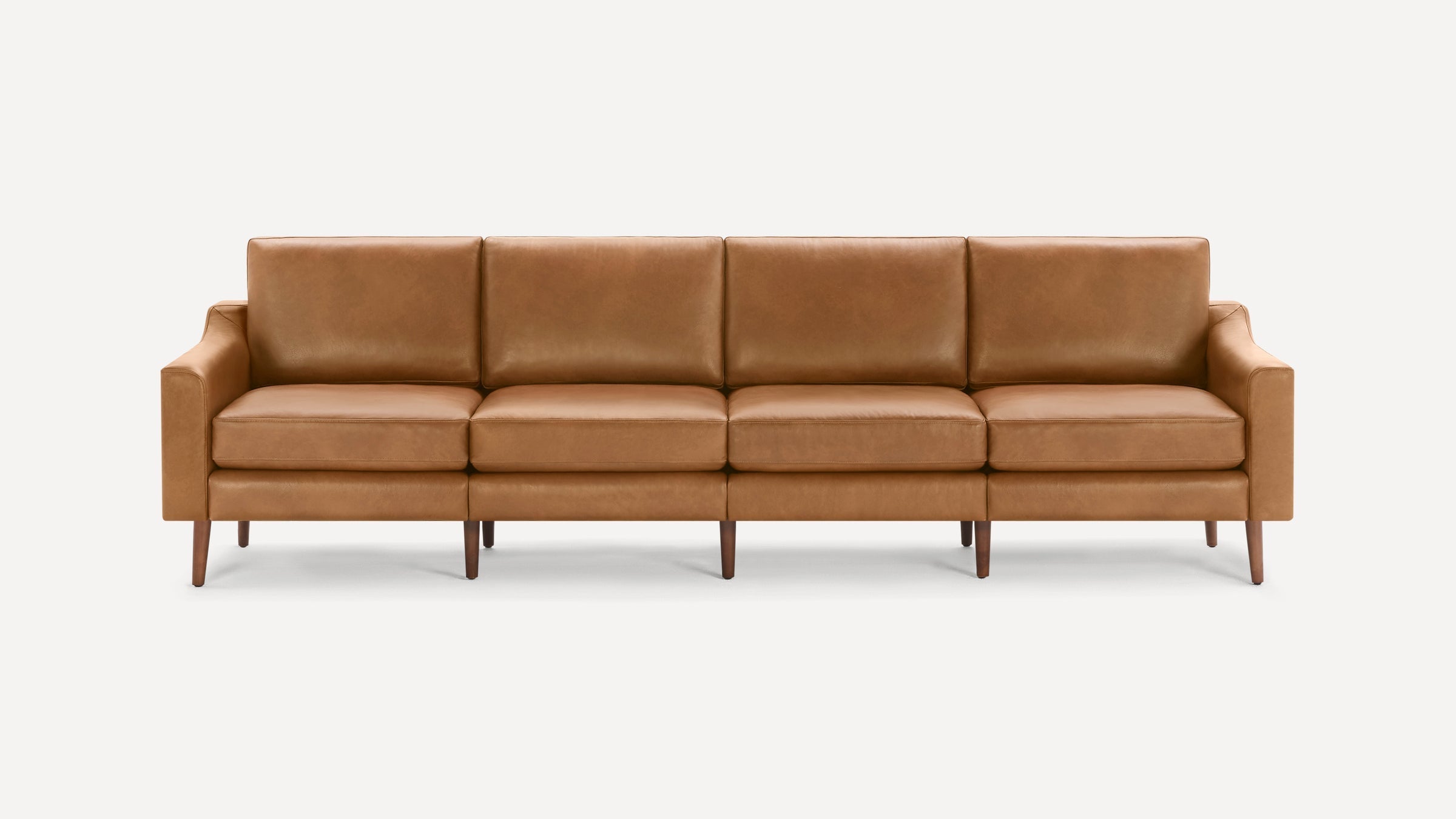 Four-seat modern mid-century style sofa with caramel brown leather upholstery and wooden tapered legs.