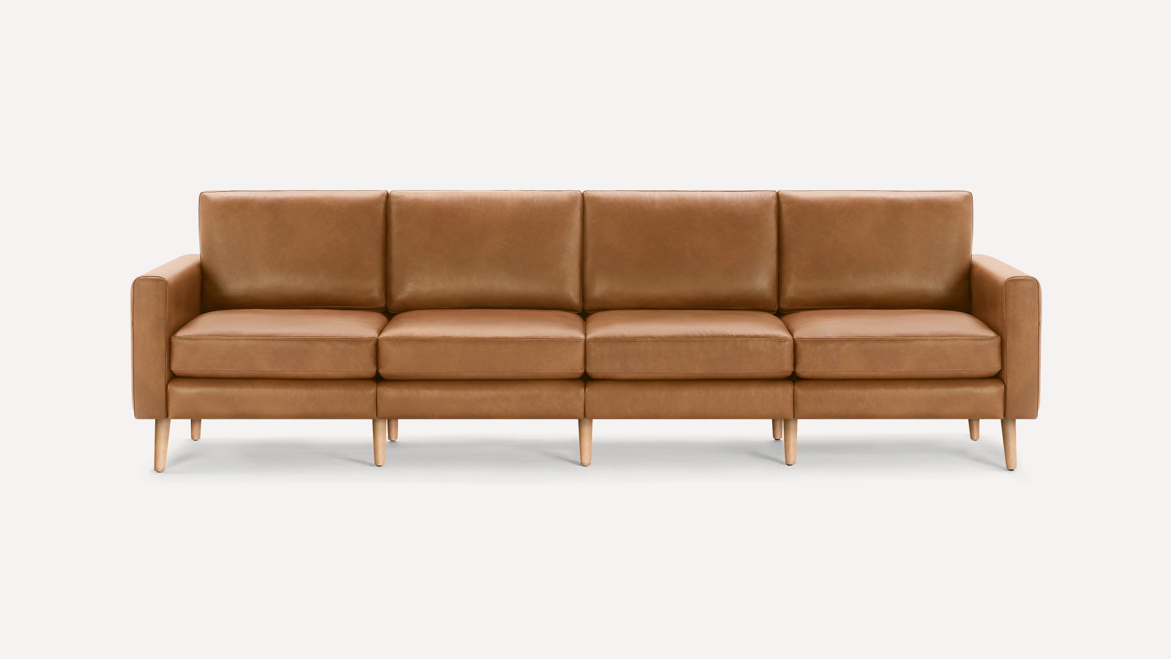 Four-seater modern sofa with tan leather upholstery, straight arms, and light wooden legs, set against a plain white background.
