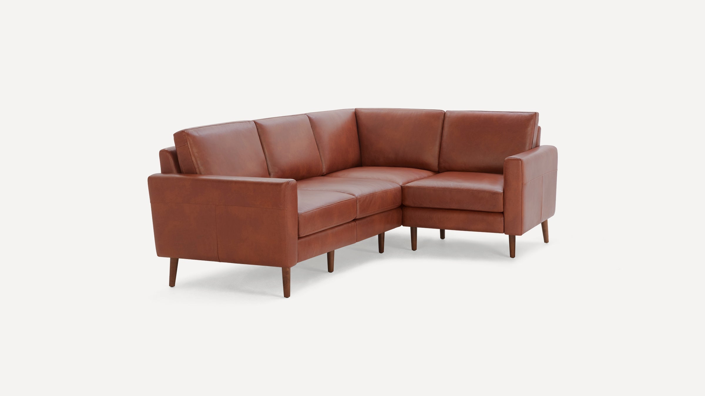 Brown leather L-shaped sectional sofa with wooden tapered legs and cushioned back and seat on white background.