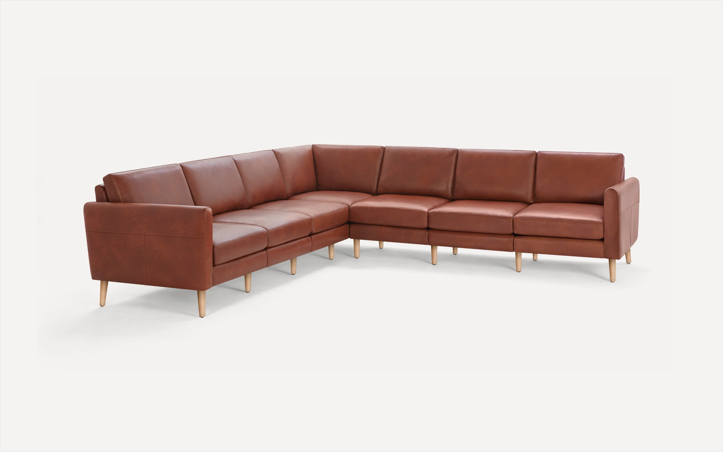 Large L-shaped sectional sofa in brown leather with wooden legs, featuring cushioned seats and backrests.