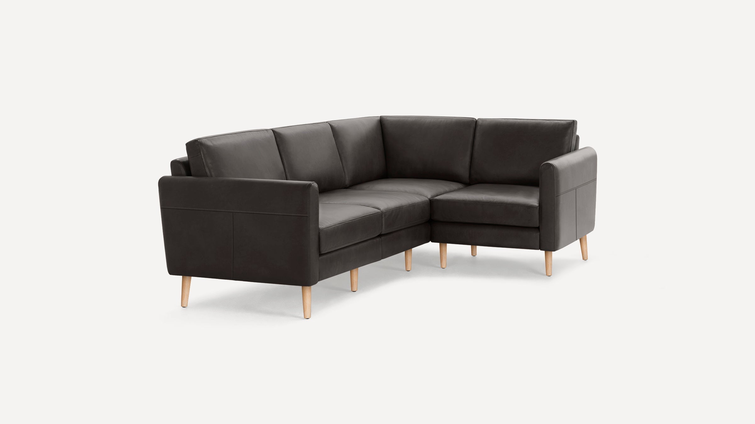 Dark gray L-shaped leather sectional sofa with wooden legs on a plain white background.