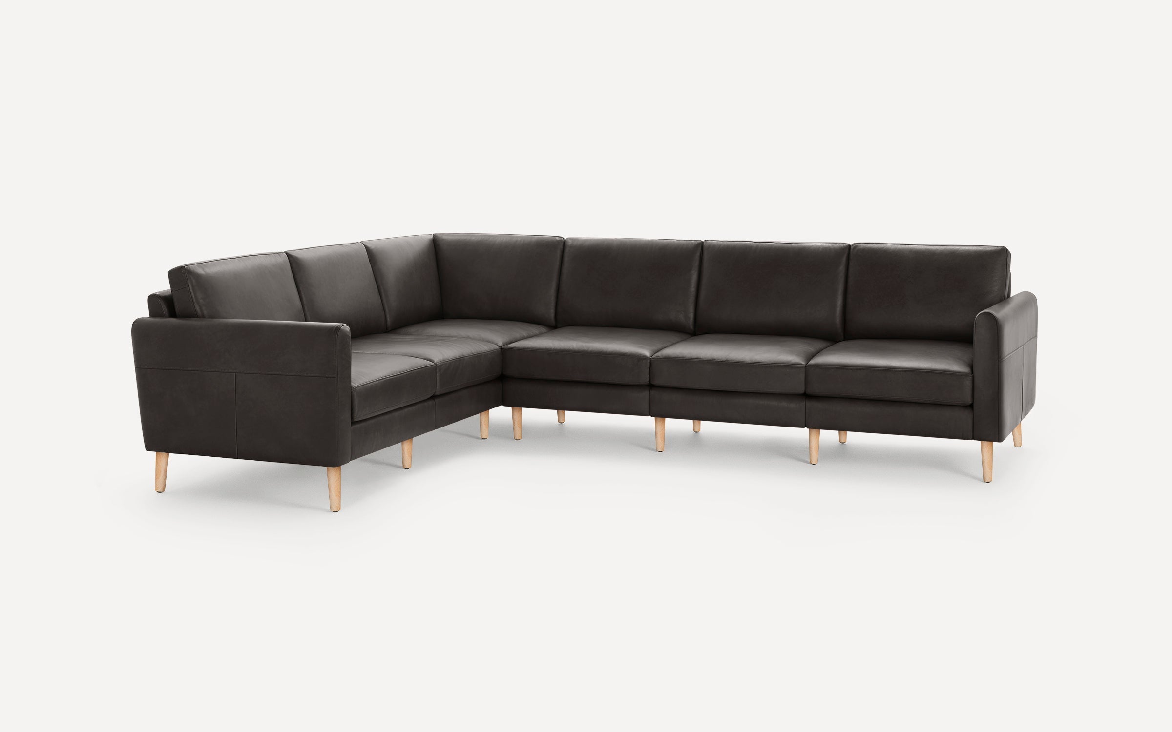 Modern L-shaped sectional sofa with dark grey leather upholstery and light wooden legs, featuring clean lines and plush cushioning.