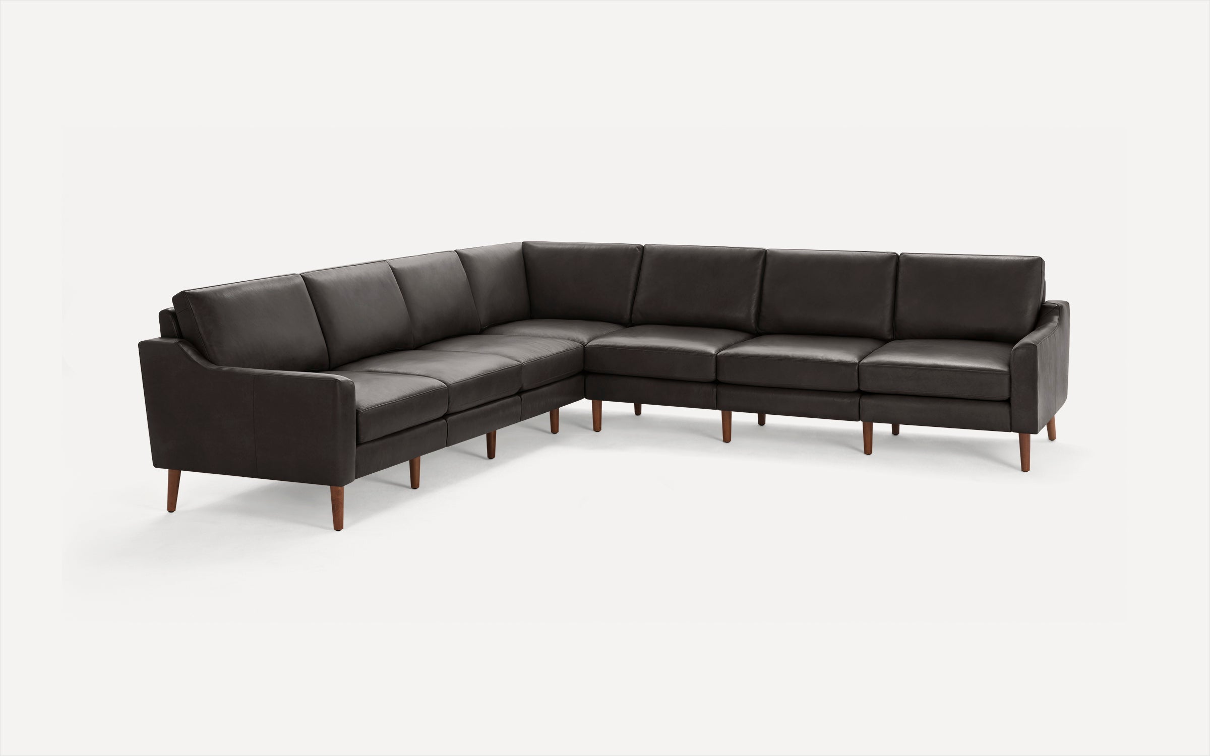 Large L-shaped sectional sofa with dark gray leather upholstery and wooden tapered legs, set against a white background.