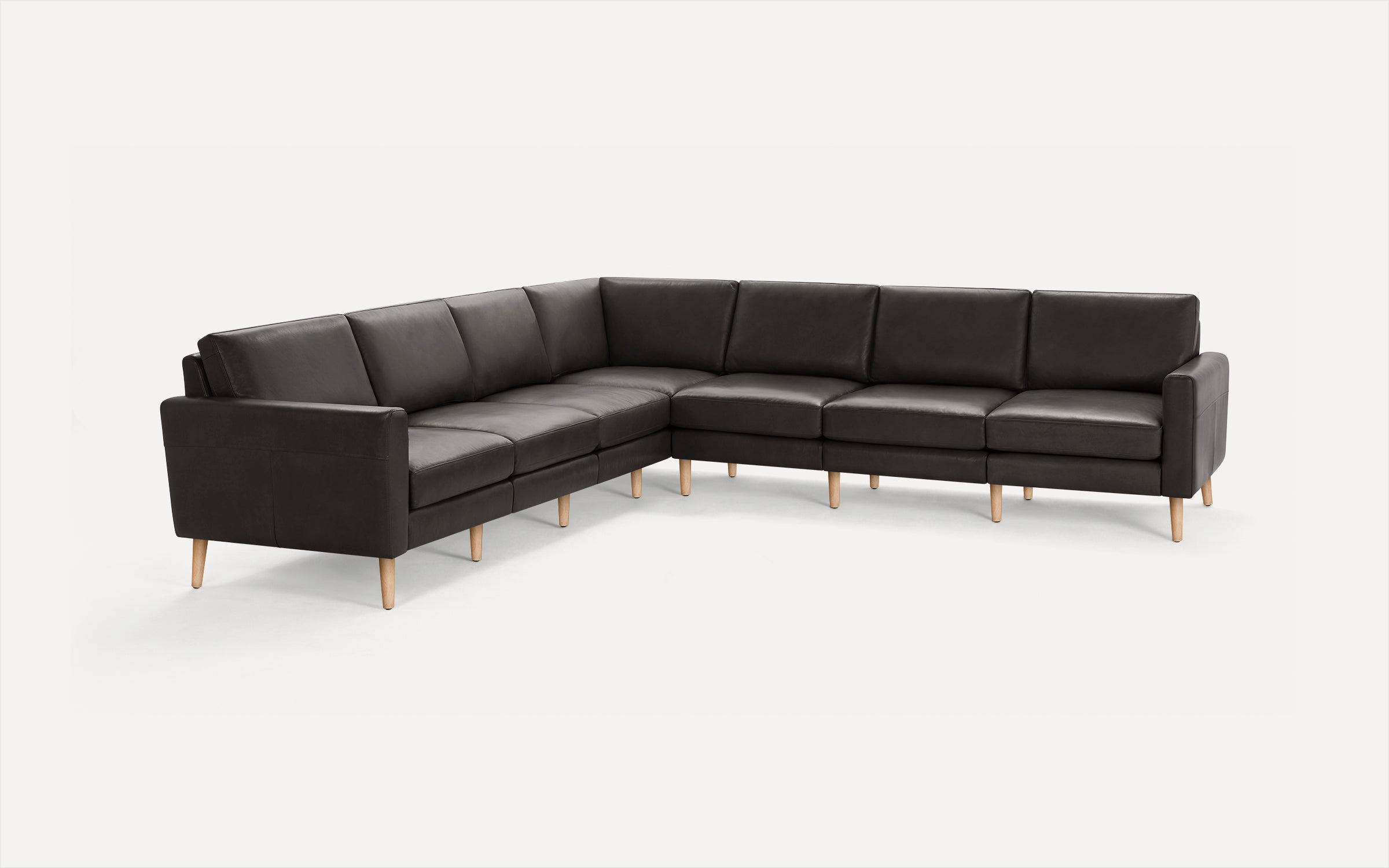 Large L-shaped sectional sofa with dark gray leather upholstery and light wooden legs on a white background.