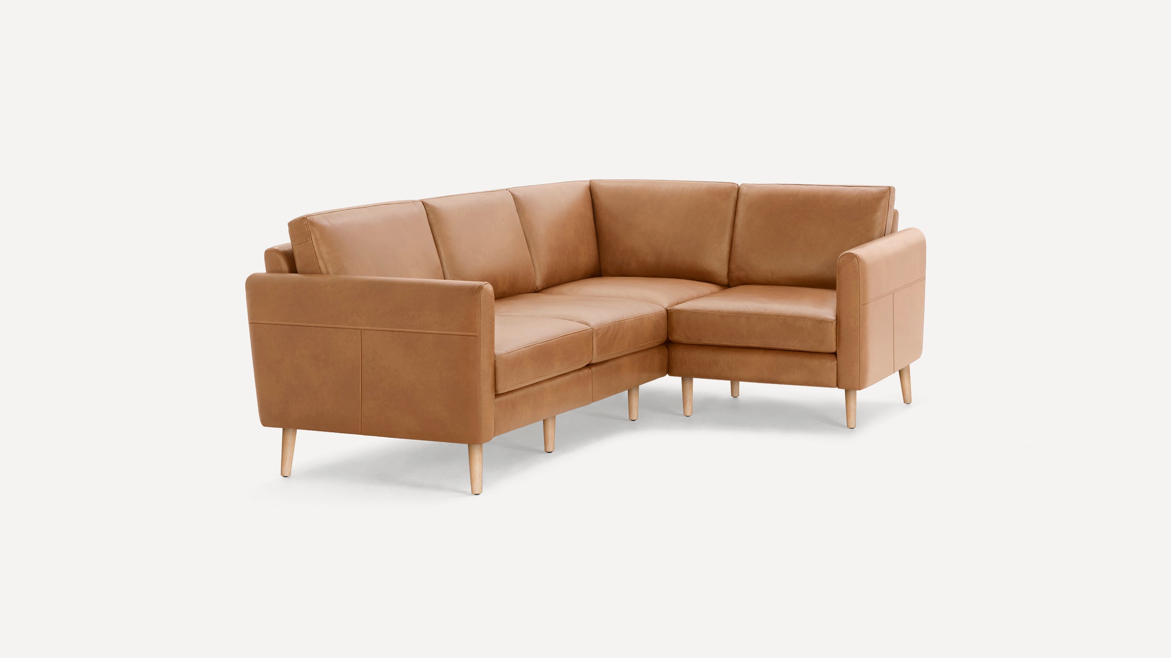Modern tan leather L-shaped sectional sofa with wooden legs, clean lines, and padded cushions on white background.