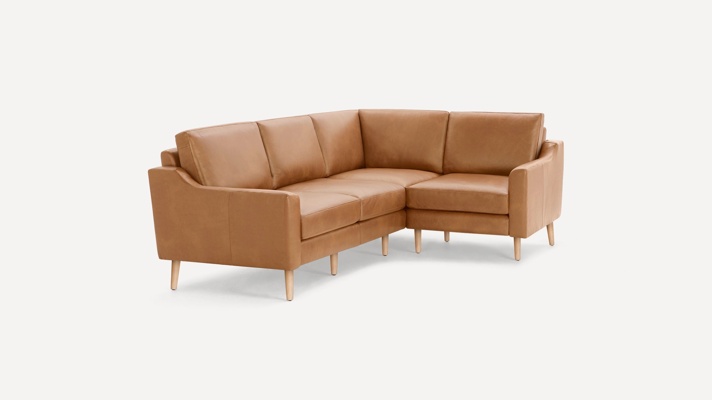 Modern tan leather L-shaped sectional sofa with wooden tapered legs on a white background.