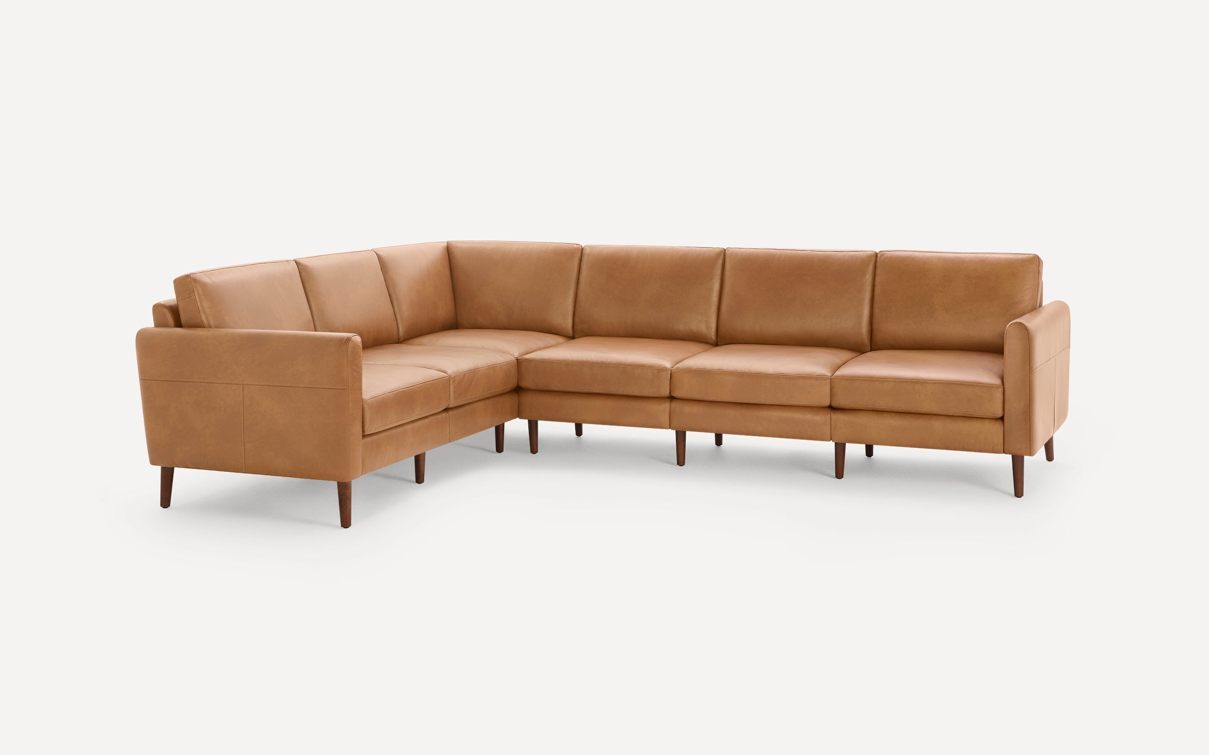 Modern L-shaped sectional sofa in tan leather with wooden legs and clean, straight lines for a sleek look.
