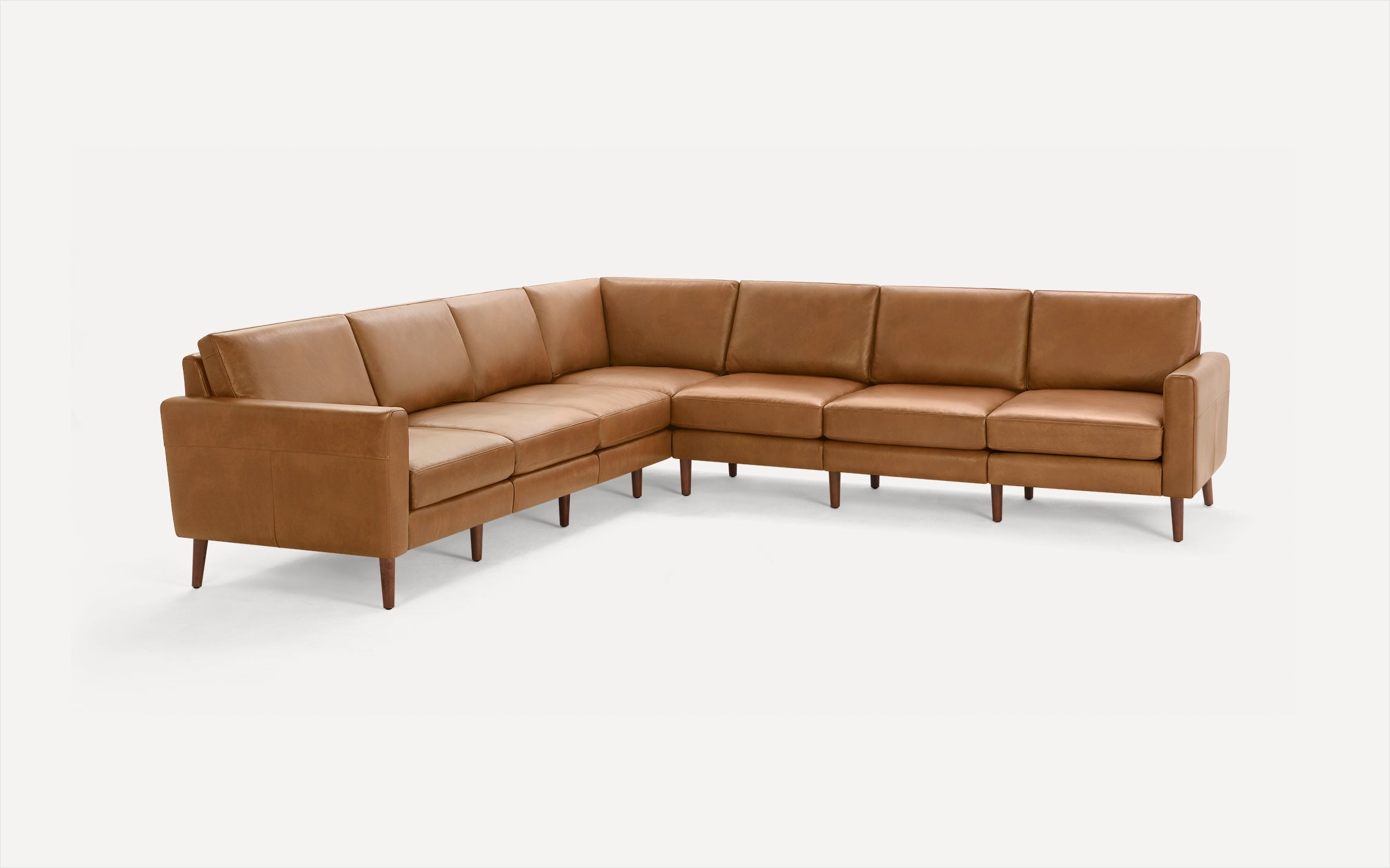 Large L-shaped sectional sofa upholstered in caramel brown leather with wooden tapered legs and clean modern design.