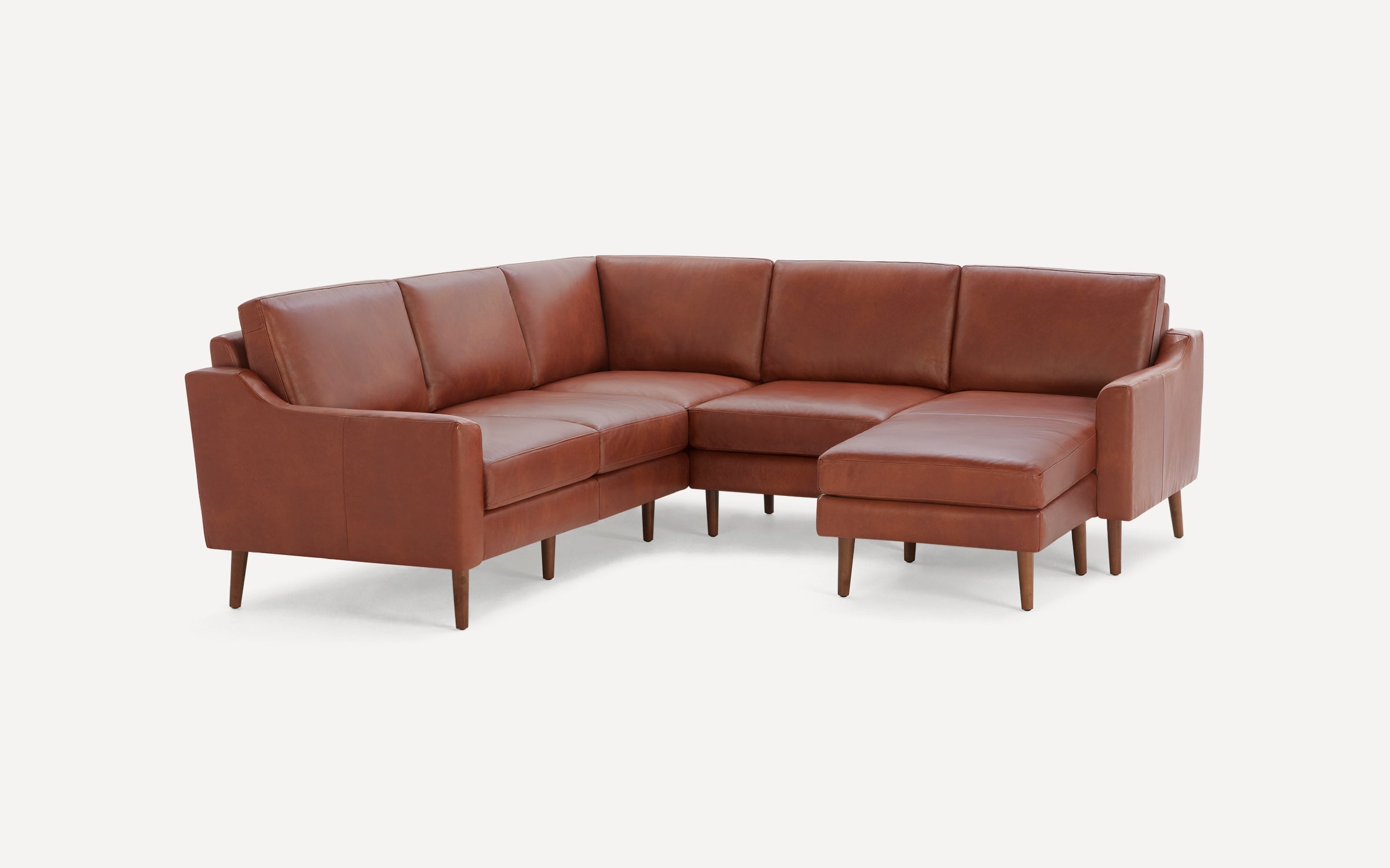 Brown leather sectional sofa with wooden legs, featuring a chaise lounge on the right side, modern and minimalist design.