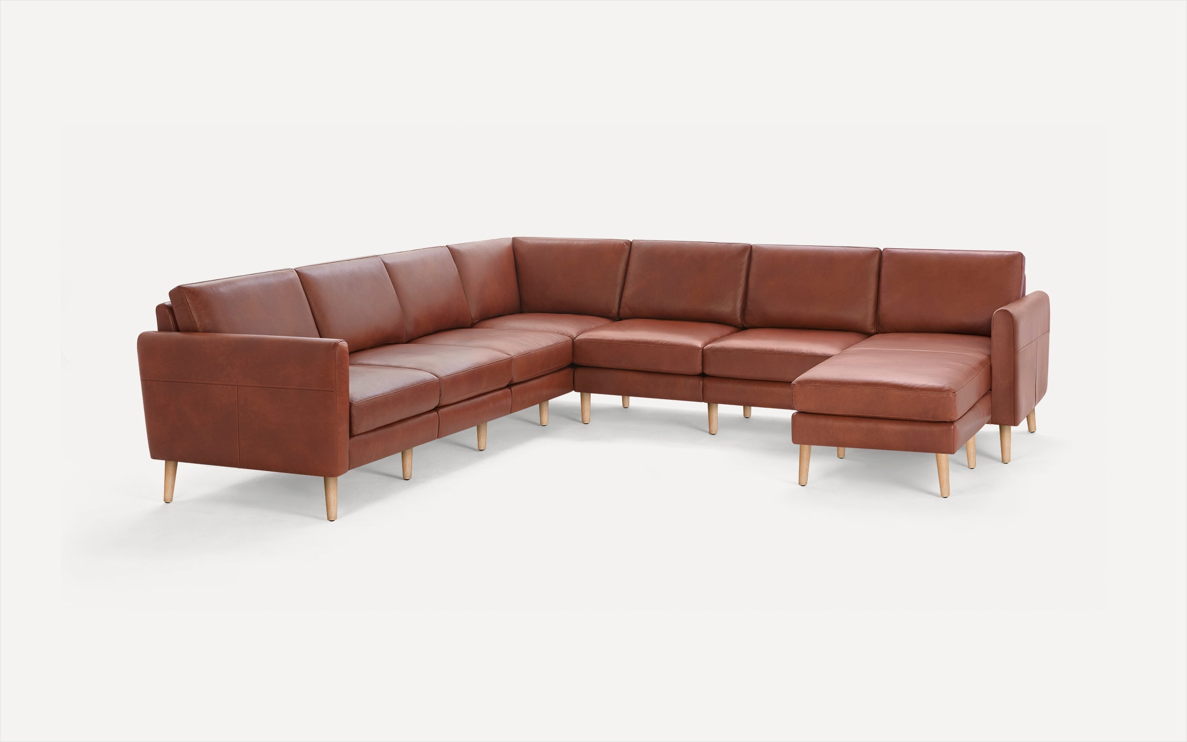 Brown leather L-shaped sectional sofa with wooden legs, featuring cushioned seats and backrests for comfortable seating.