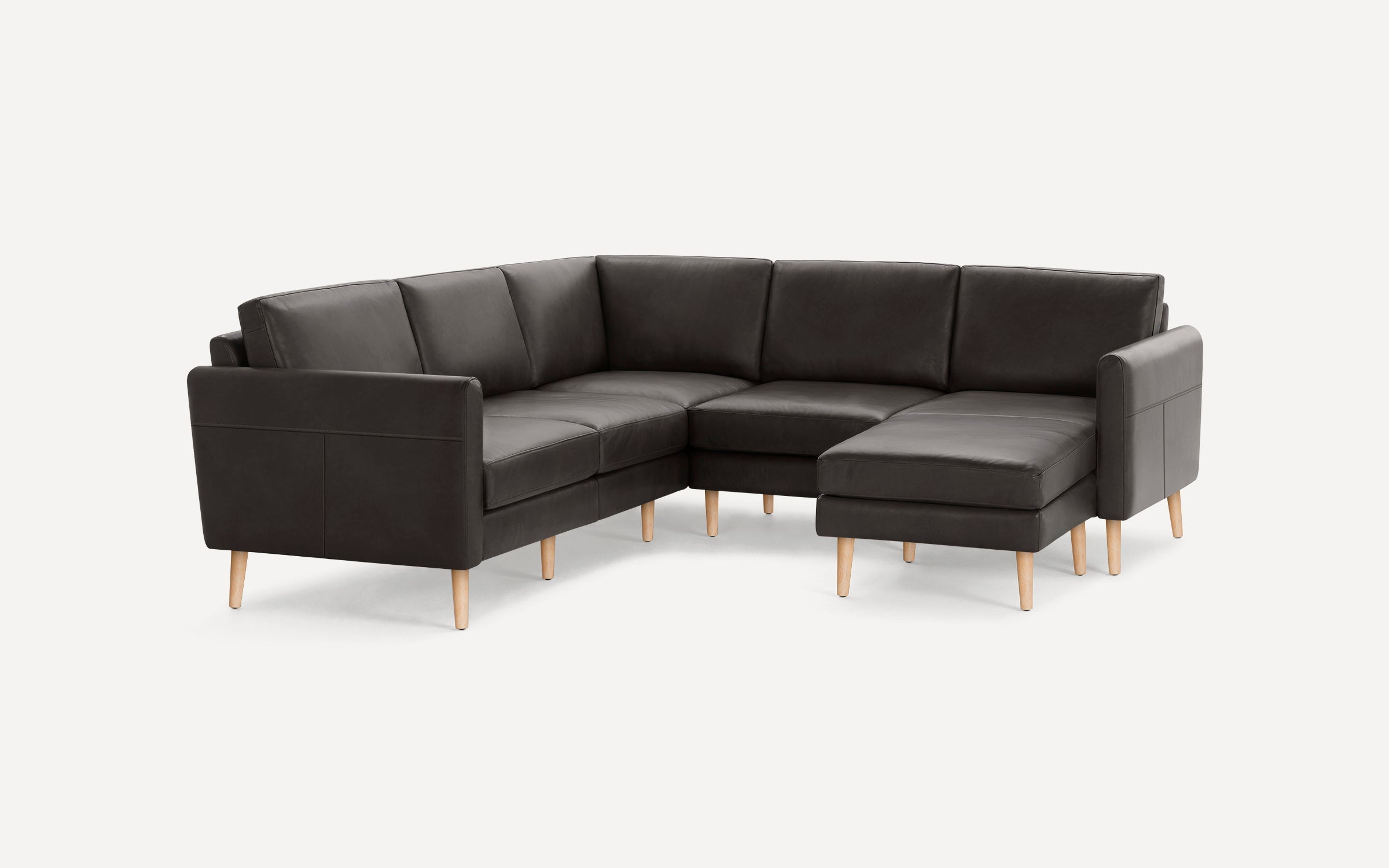 Modern dark gray L-shaped leather sectional sofa with wooden legs, featuring a chaise lounge on the right side.