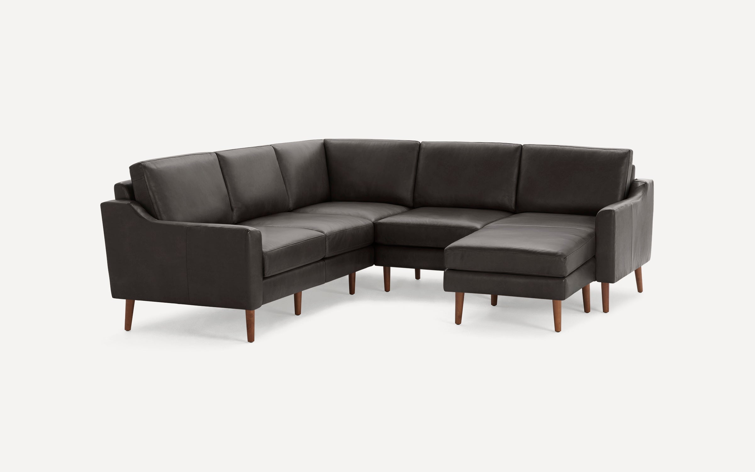 Dark gray leather L-shaped sectional sofa with tapered wooden legs and cushioned seats and backs on white background.