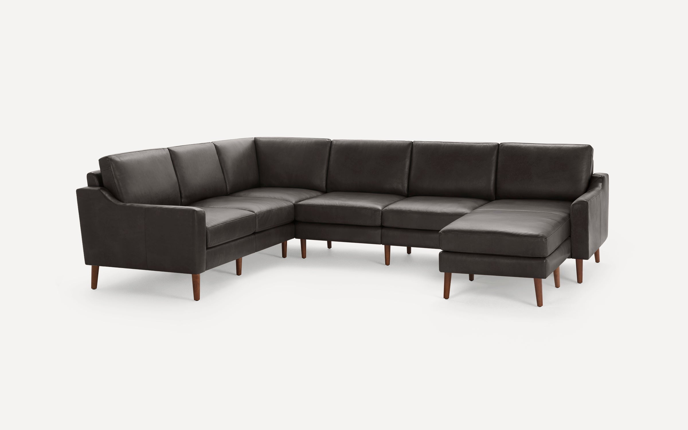 Modern dark brown leather sectional sofa with wooden legs, featuring a chaise lounge on the right side.