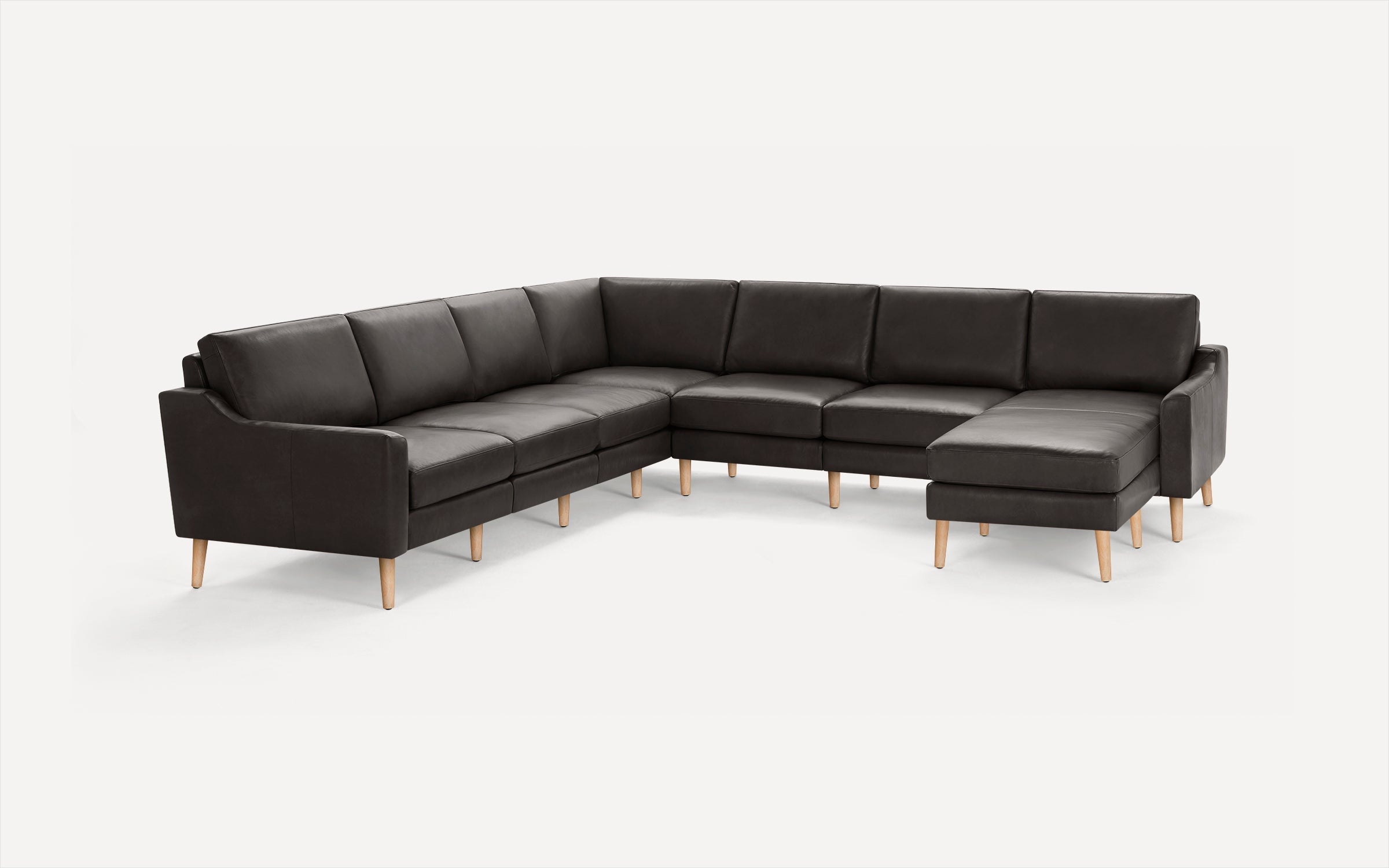 Modern dark brown leather sectional sofa with wooden legs, featuring a chaise lounge on the right side.