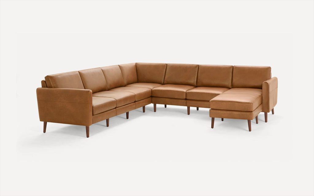 Large brown leather sectional sofa with wooden legs, featuring an L-shape design and cushioned seats and backs.