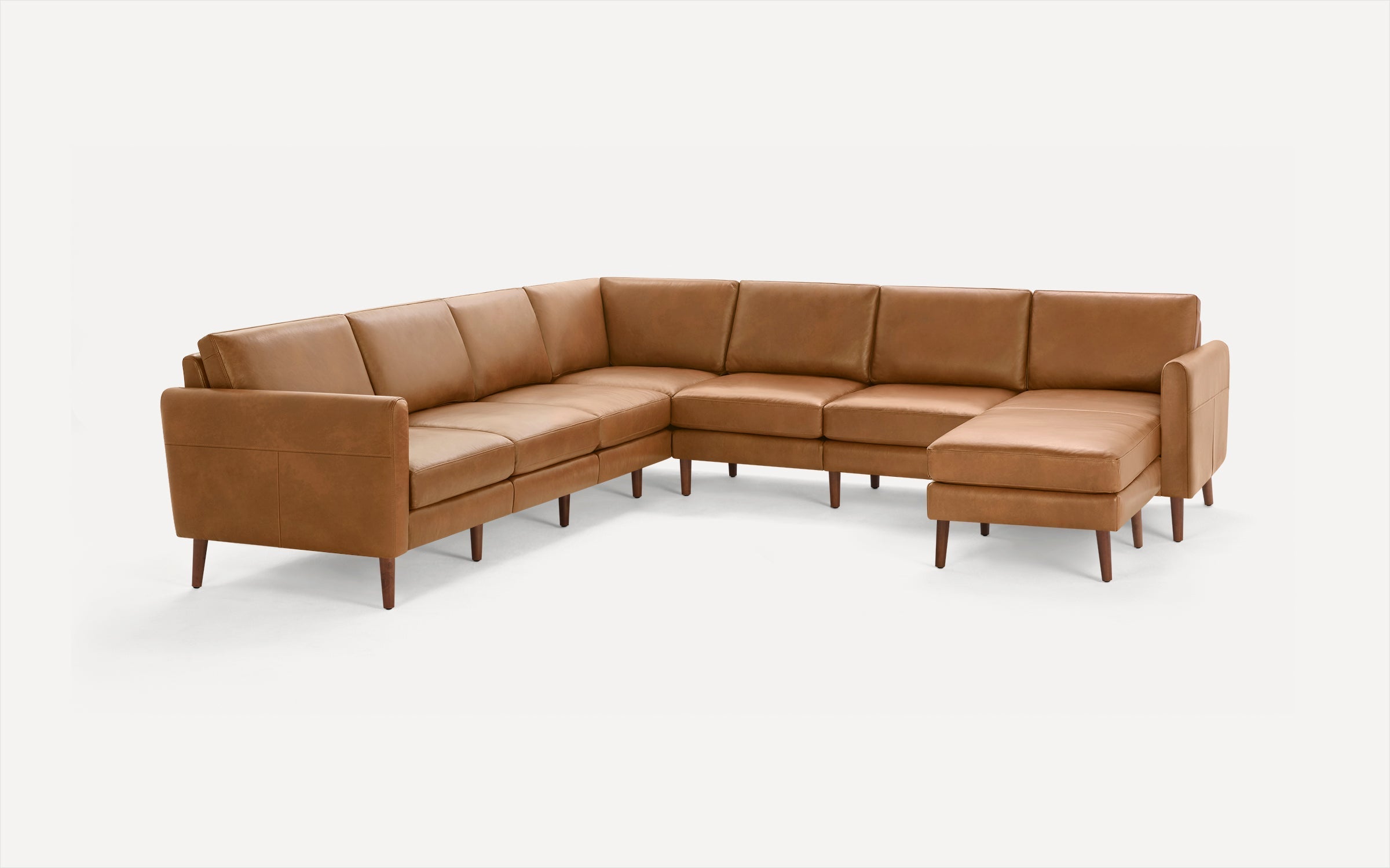 Large brown leather sectional sofa with wooden legs, featuring an L-shape design and cushioned seats and backs.