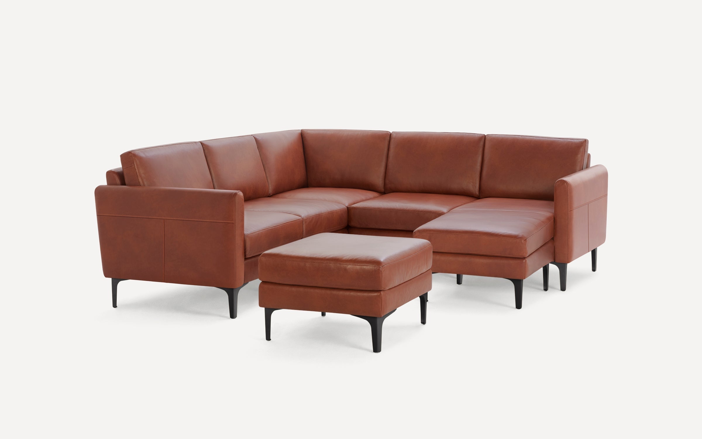 Brown leather sectional sofa with matching ottoman, featuring black tapered legs and clean, modern design.