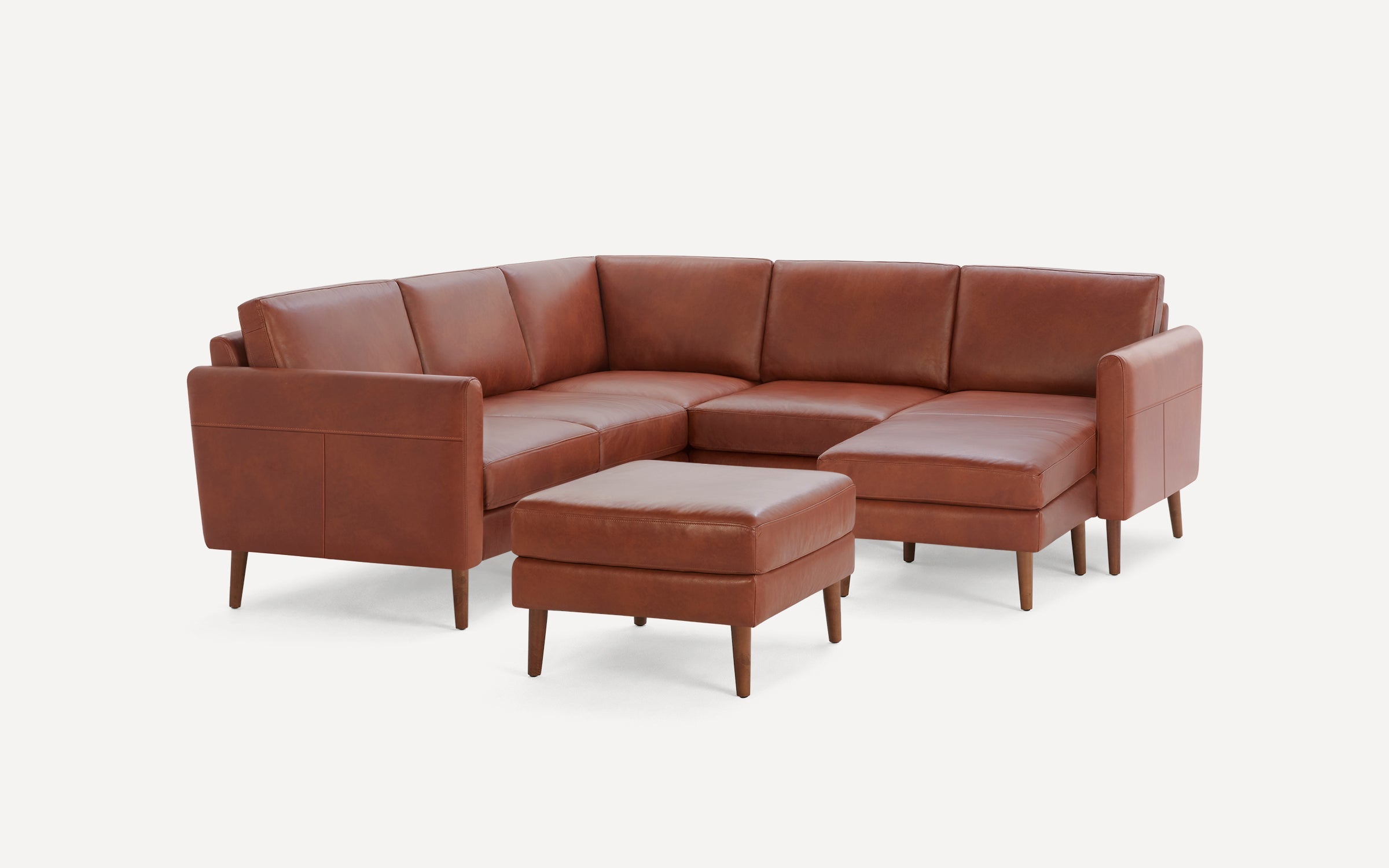 Modern brown leather sectional sofa with clean lines and wooden legs, accompanied by a matching ottoman, on a white background.